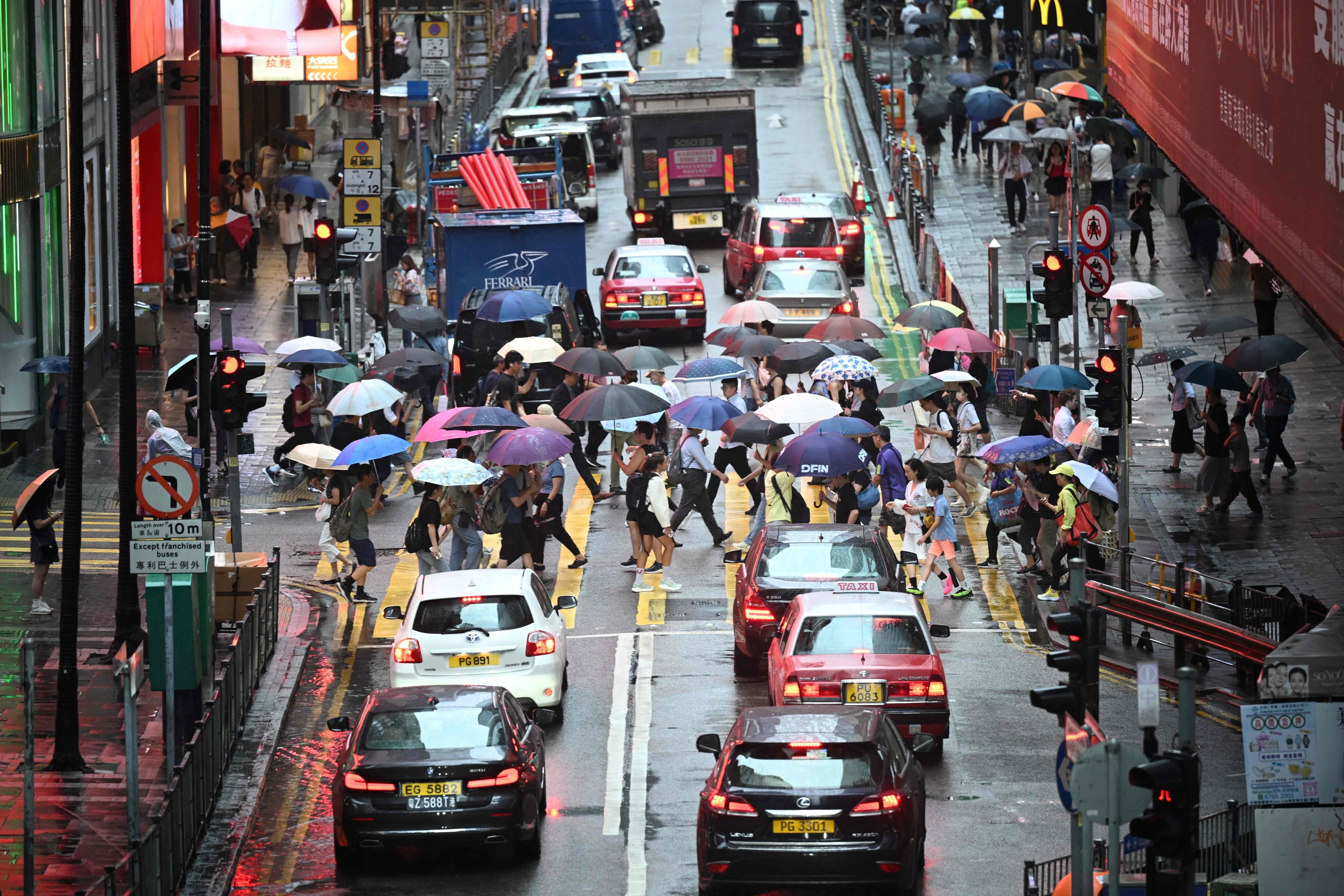 Pedestrians and cars make their way in heavy rain in Hong Kong on July 10, after the Observatory issued a red rainstorm warning signal. Photo: AFP