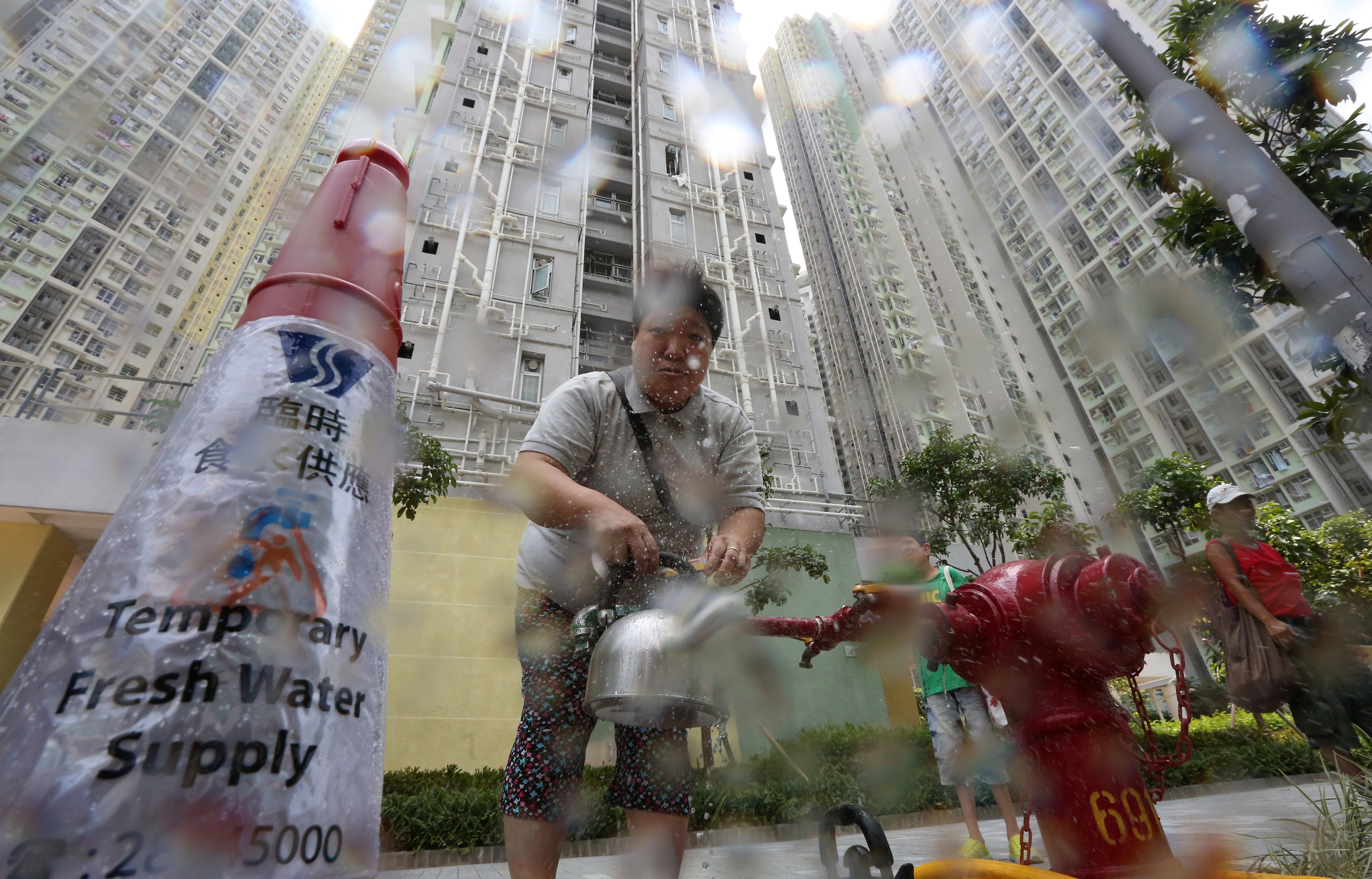 A resident of Kai Tak’s Kai Ching Estate stocks up on water from a temporary tap on July 11, 2015, as excessive amounts of lead were found in fresh water samples from the public housing complex. File photo: Felix Wong