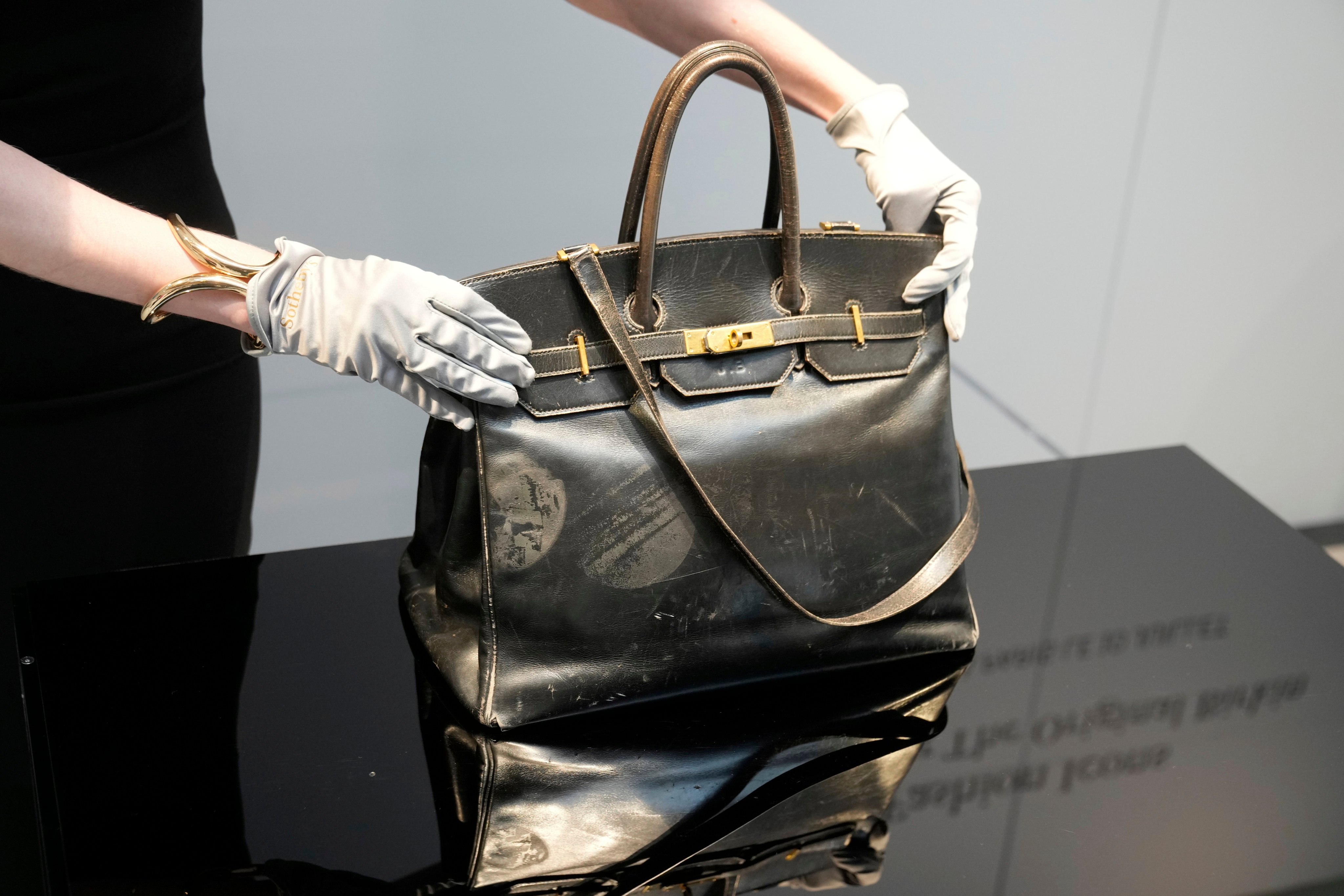 An auction officer displays the original Birkin bag created by Hermès for Jane Birkin in 1984, before its auction in Paris on Thursday. Photo: AP
