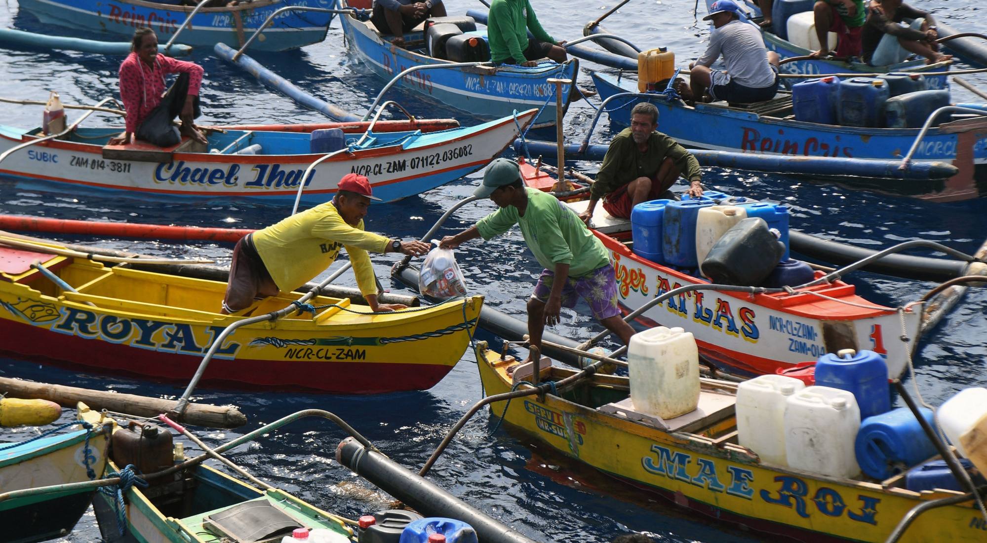 Fishermen aboard their wooden boats passing on a bag of food supplied by a Philippine Bureau of Fisheries and Aquatic Resources ship near the Chinese-controlled Scarborough Shoal in disputed waters of the South China Sea. Photo: AFP Fishermen aboard their wooden boats passing on a bag of food supplied by a Philippine Bureau of Fisheries and Aquatic Resources ship near the Chinese-controlled Scarborough Shoal in disputed waters of the South China Sea. Photo: AFP