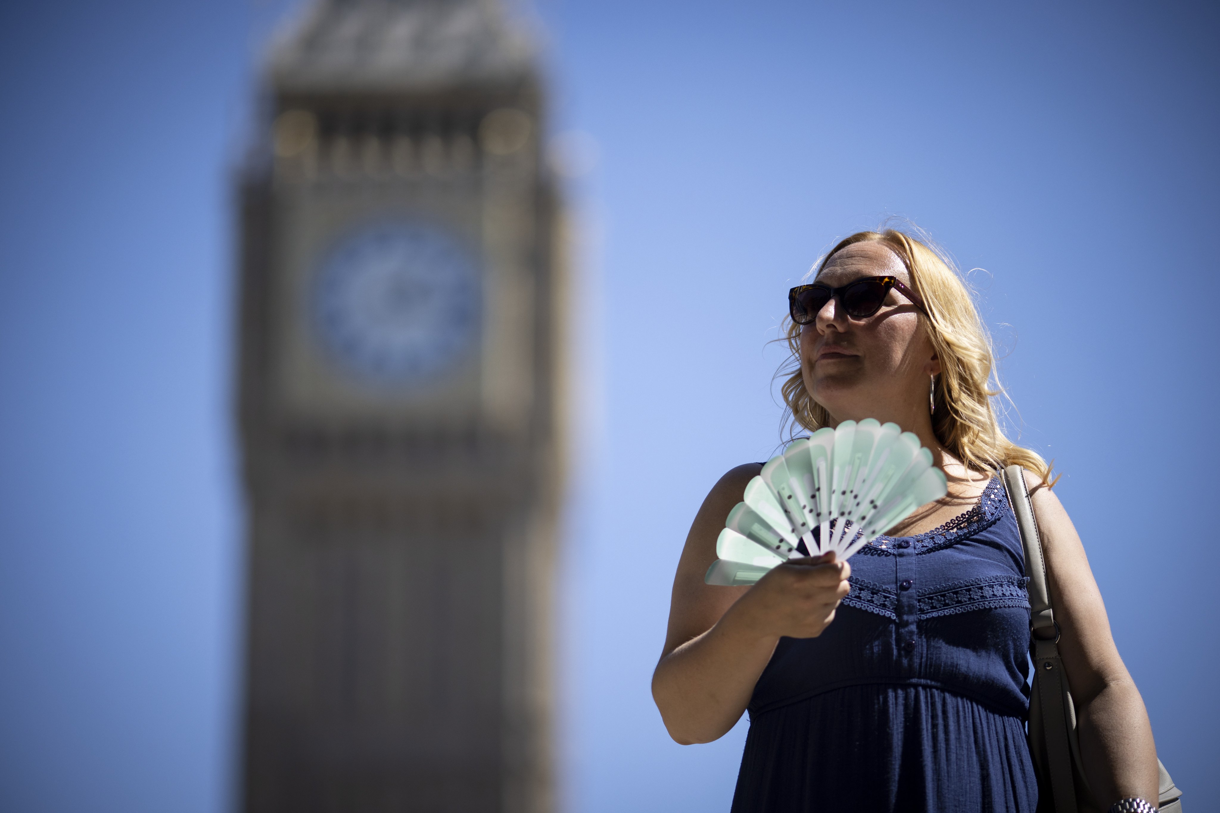A tourist in London uses a fan to cool off. File photo: EPA-EFE