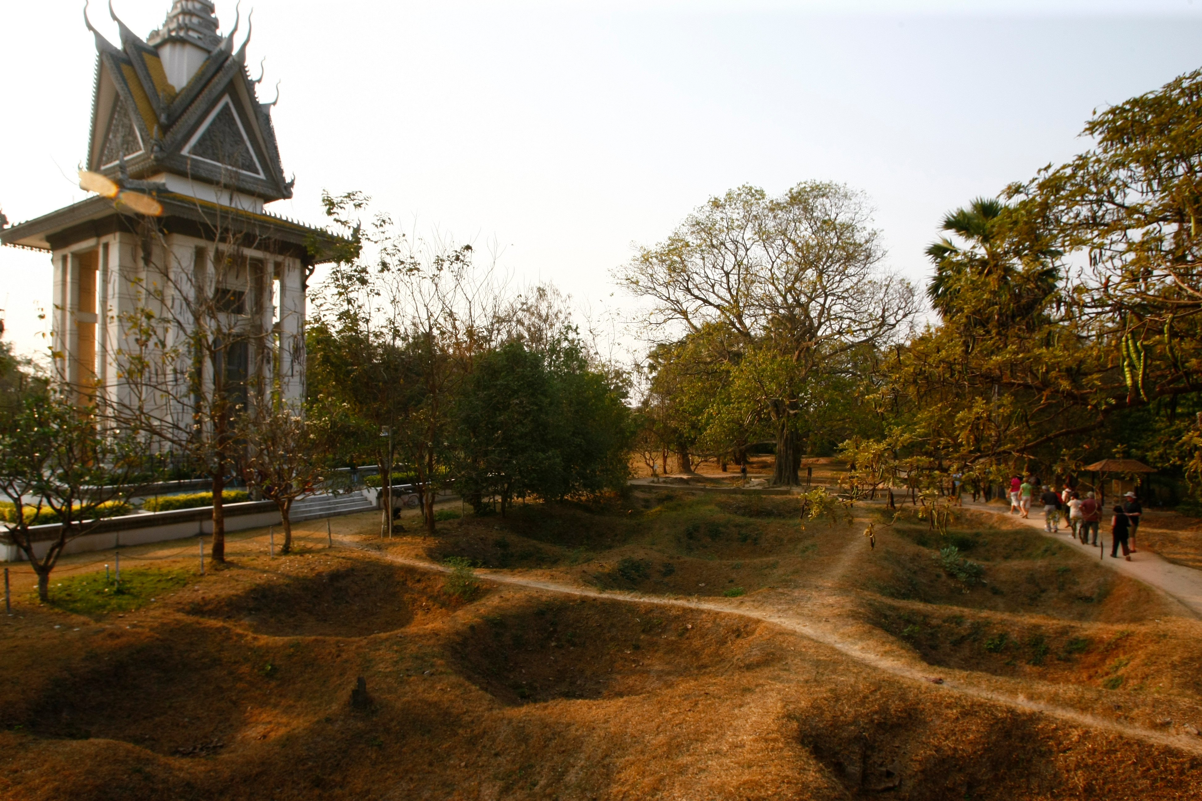 Visitors walk by the mass grave of the victims of the Khmer Rouge regime next to a memorial stupa filled with victims’ skulls at the Choeung Ek killing field in Phnom Penh, Cambodia. Photo: AP