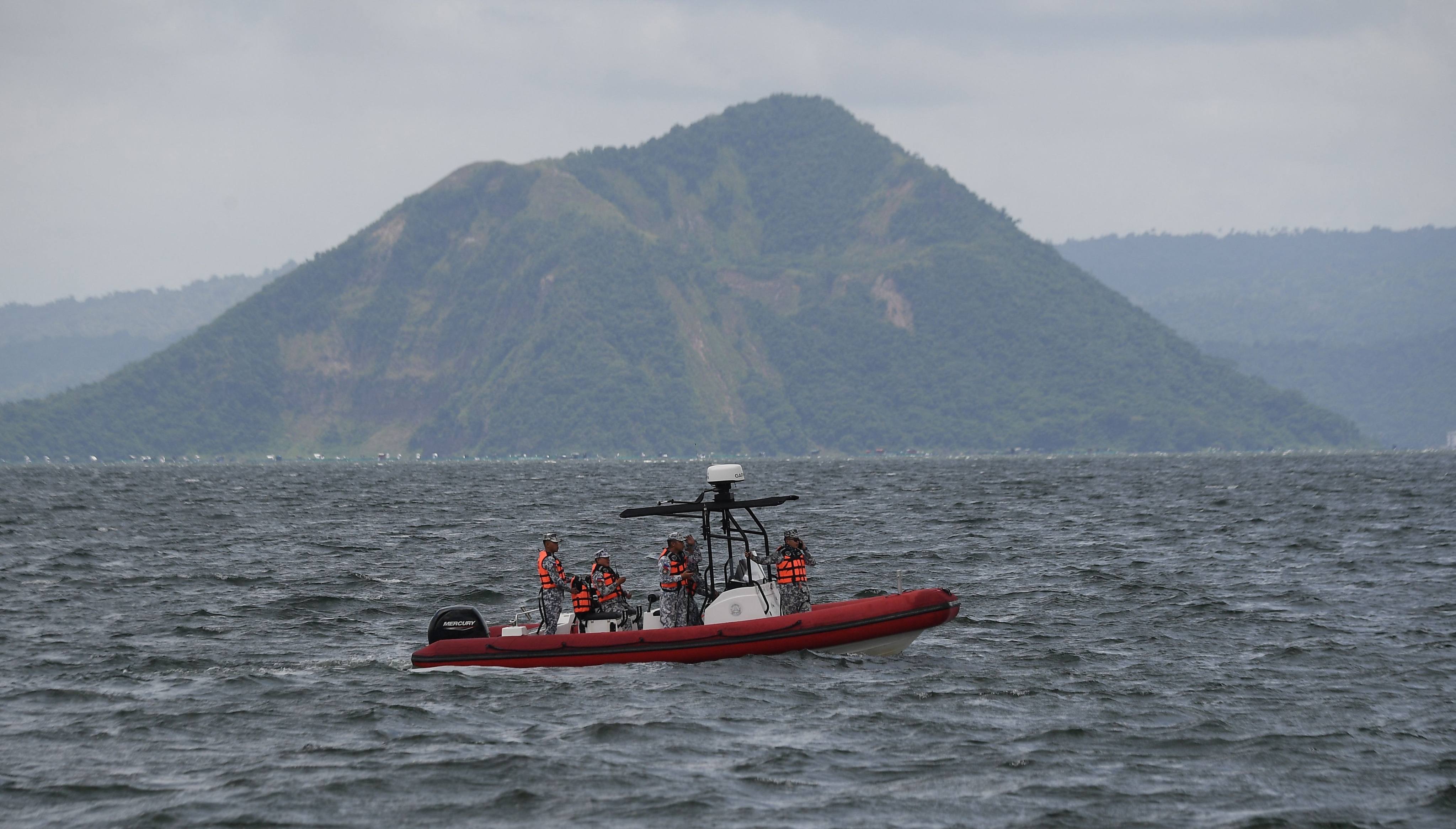 Philippine coastguard personnel aboard an inflatable boat speeds past one of Taal craters on their way to the site where the bodies of cock fighters were allegedly dumped in Taal Lake off Laurel town, Batangas province south of Manila on Thursday. Photo: AFP