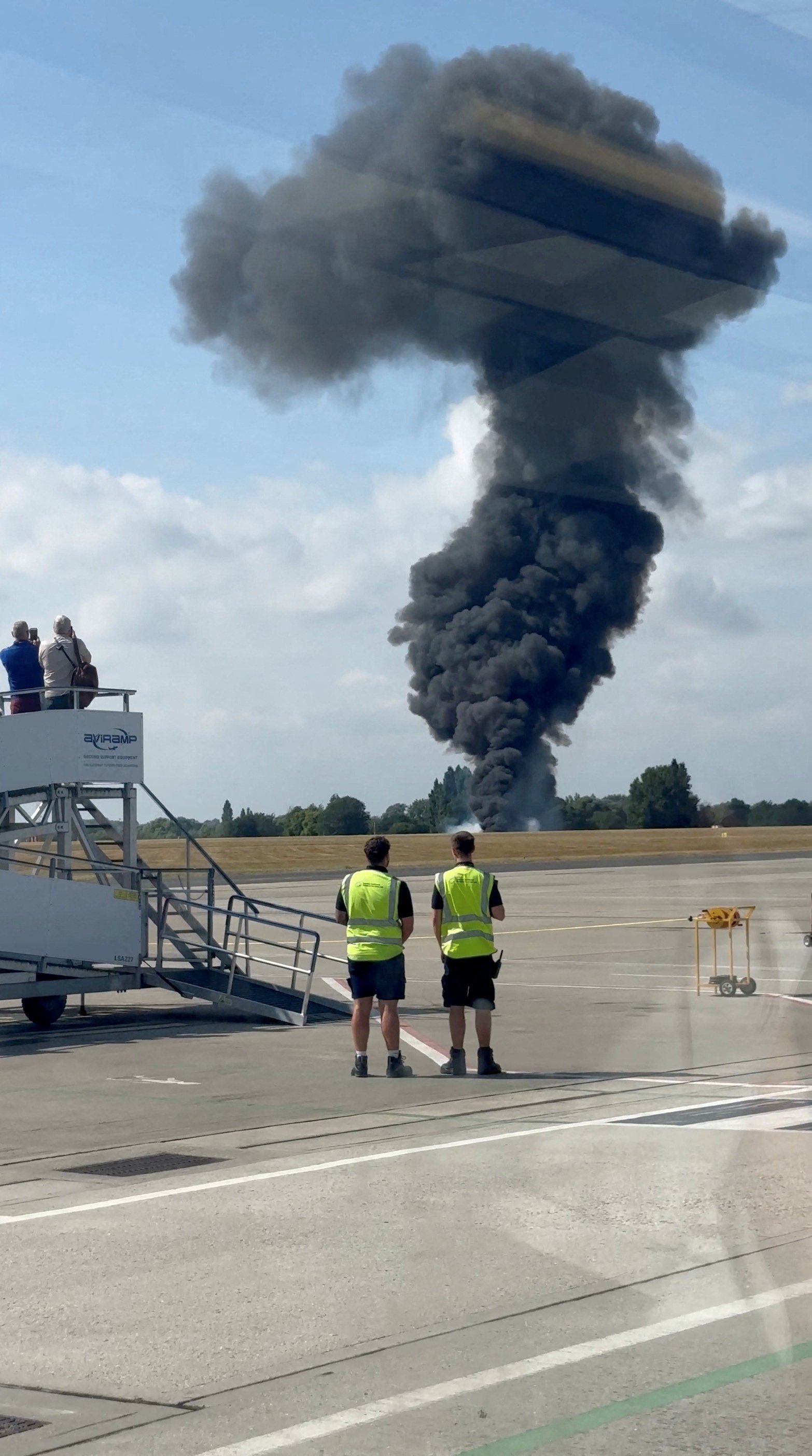 A plume of black smoke rises from an area near the runway after a small plane crash, as seen from inside a building at London Southend Airport, in Southend, Britain on Sunday. Photo: X/ @agussromagnoli/Reuters