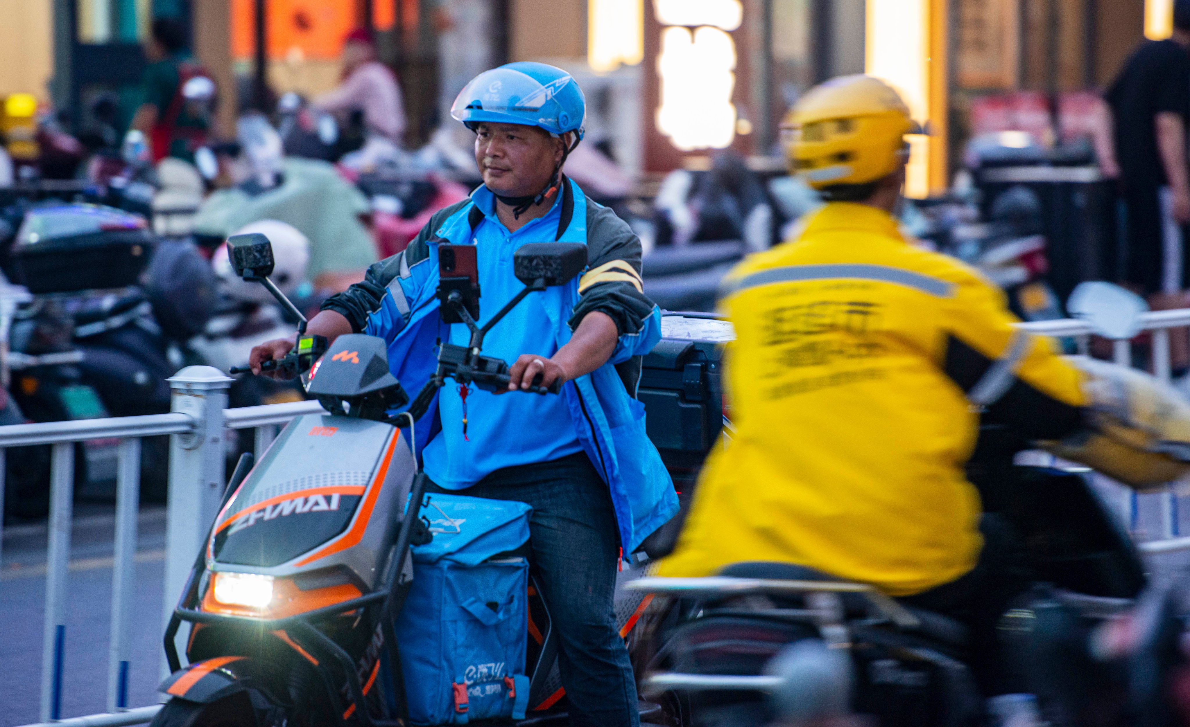 Delivery workers for Ele.me and Meituan pass on a street in Yancheng, in China’s eastern Jiangsu province, on May 14, 2025. Photo: VCG via Getty Images