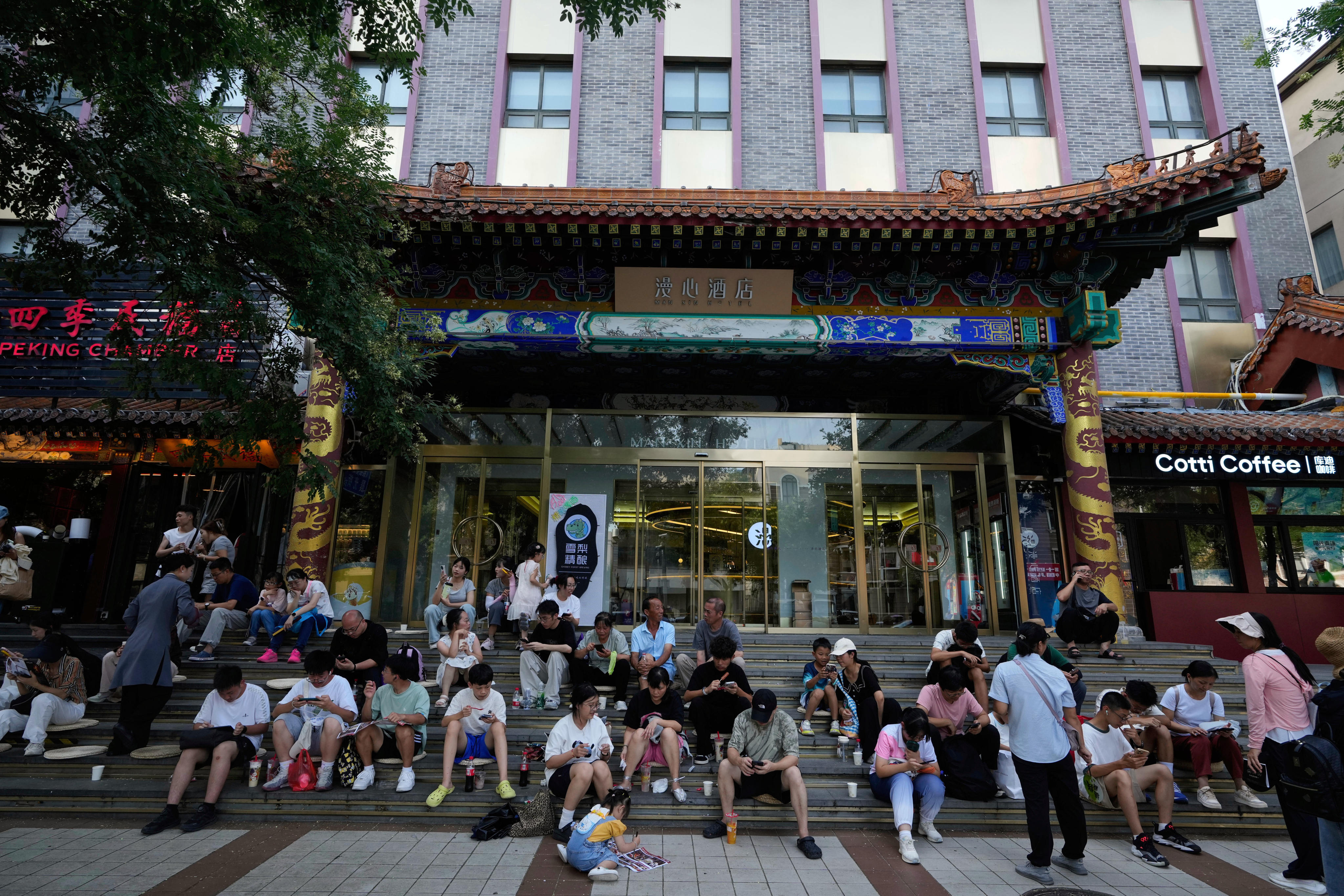 People scroll through their phones while sitting in front of a hotel in Beijing on July 13. Photo: AP