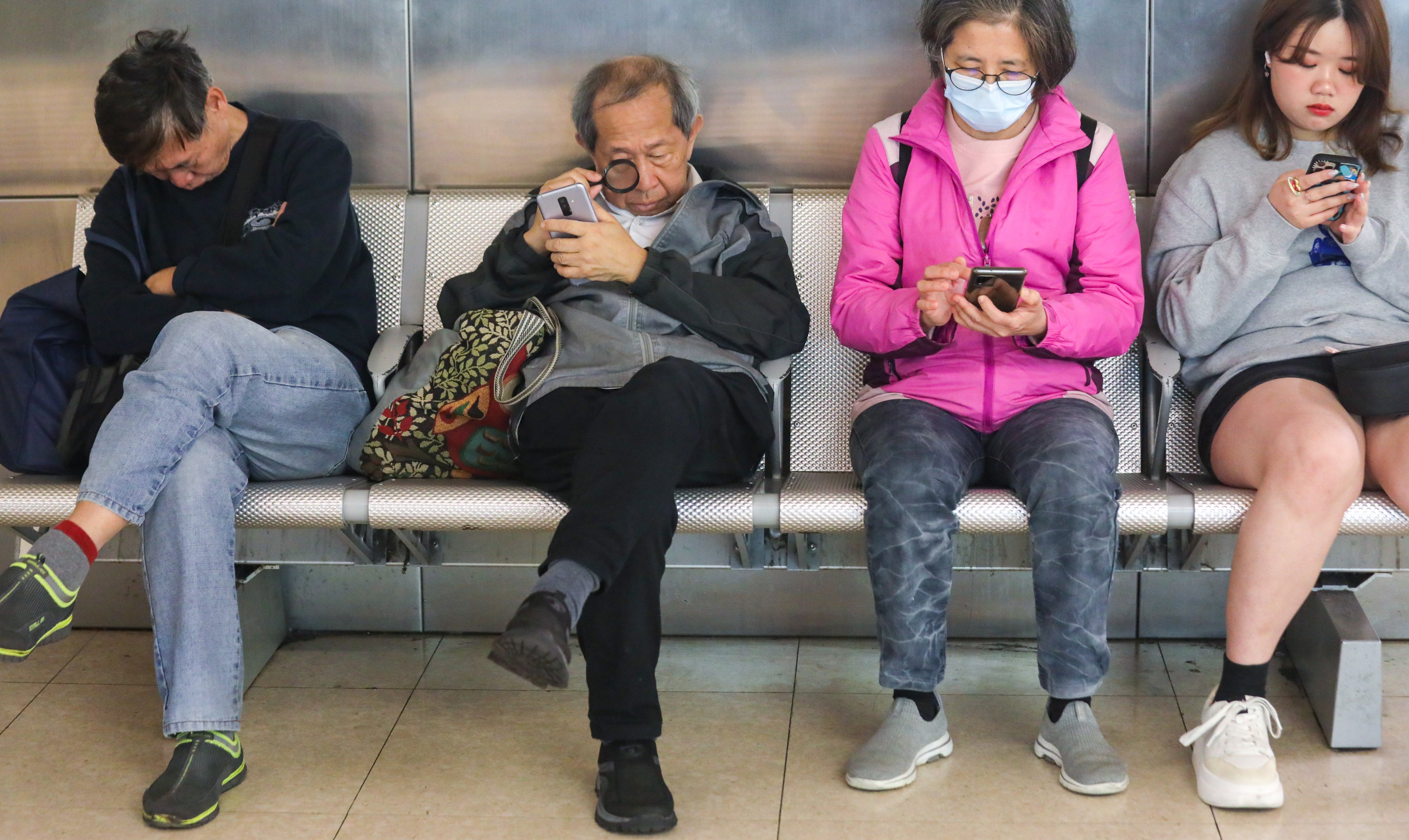 An elderly man looks at his mobile phone screen with the aid of a magnifying glass in Tsim Sha Tsui. Photo: Xiaomei Chen