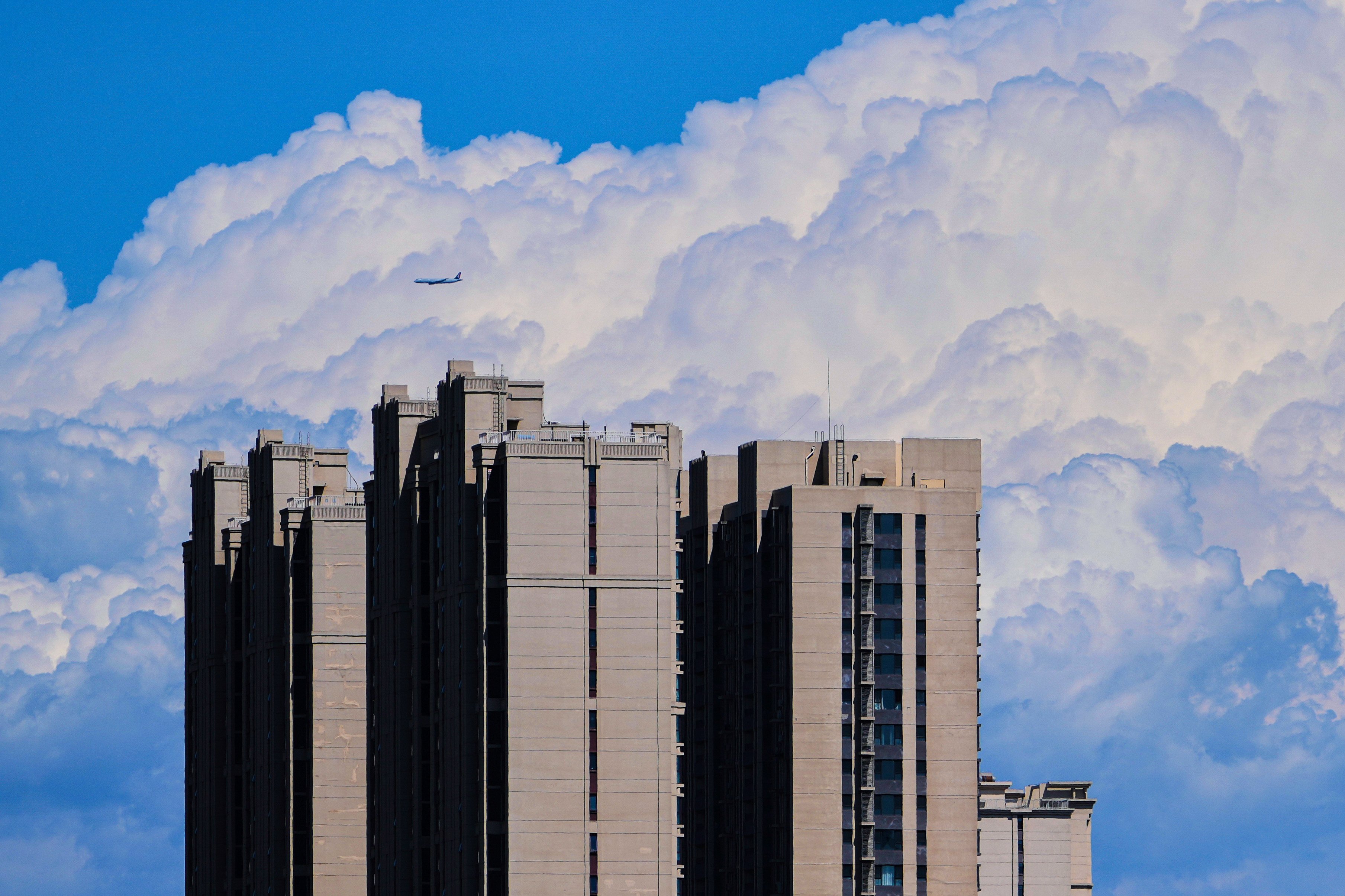 A passenger airliner flies past the clouds near a residential building in Beijing on July 13, 2025. Photo: AP