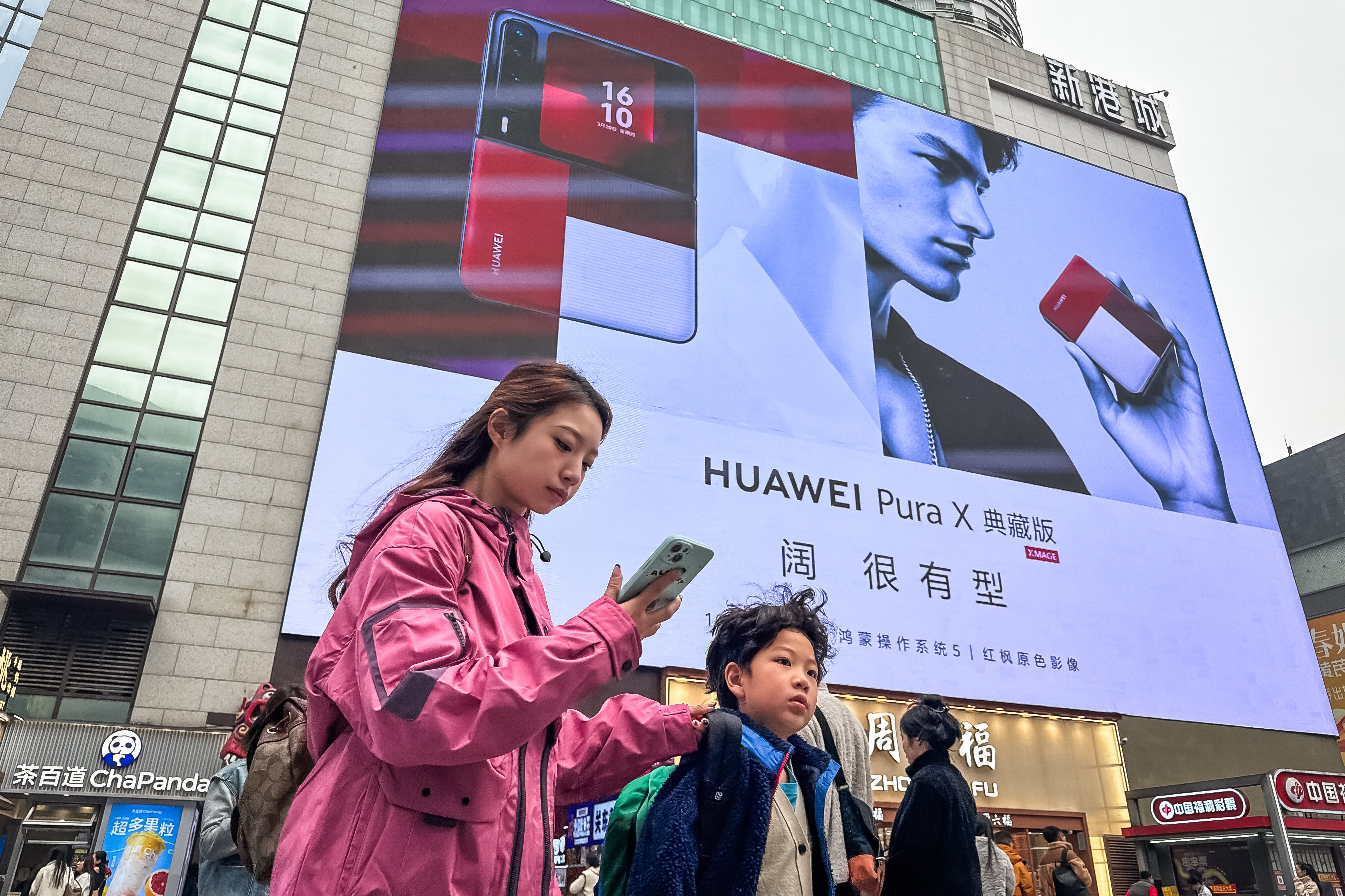 Pedestrians walk past a billboard featuring the  Huawei Pura X Classic Edition smartphone in March, in Chongqing, China. Photo: Getty Images