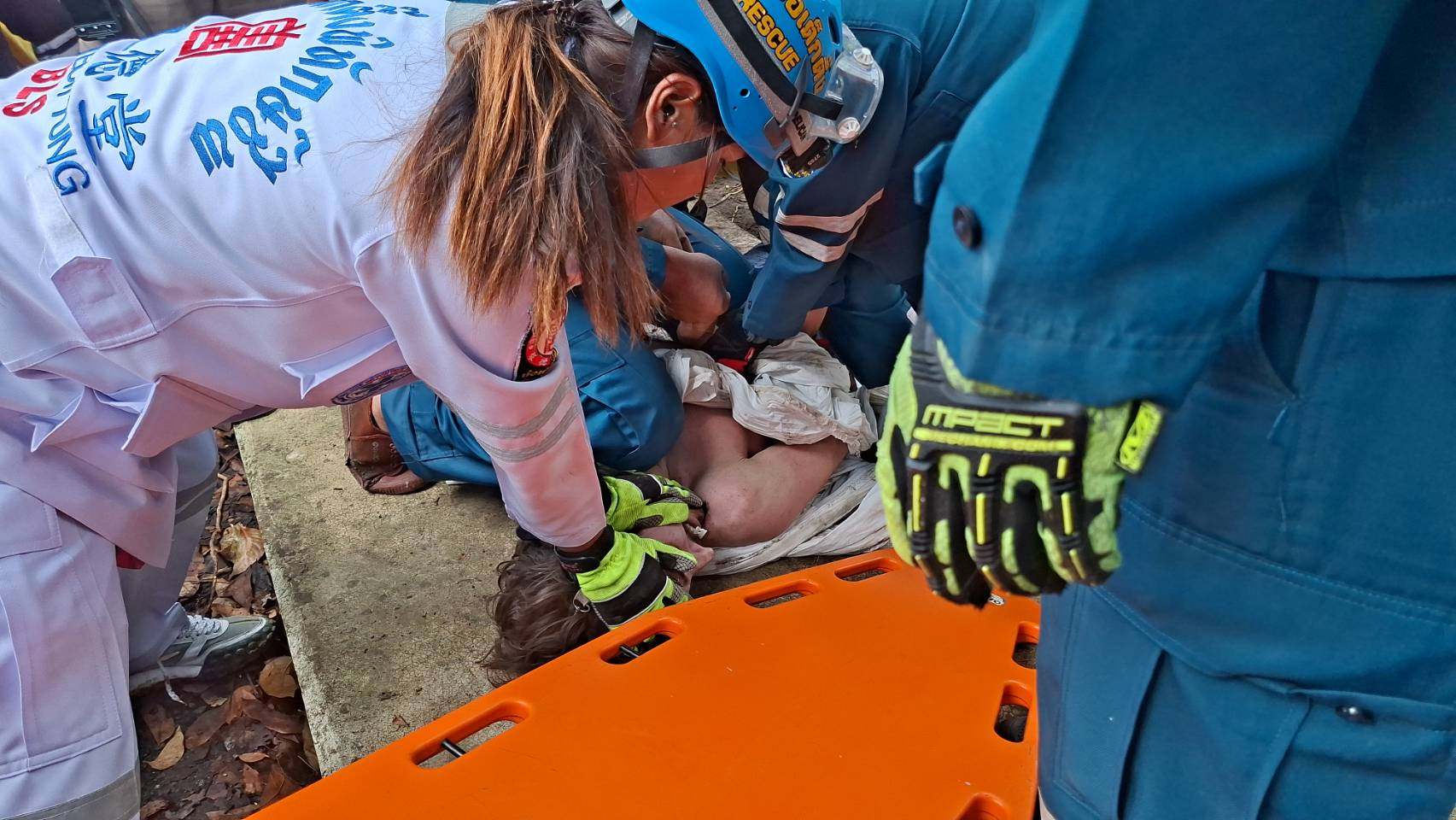 Thai rescuers attending to Jack after he fell through a gap in the concrete slabs covering a drain separating his condo building from a canal in Bangkok. Photo: Poh Teck Tung Foundation