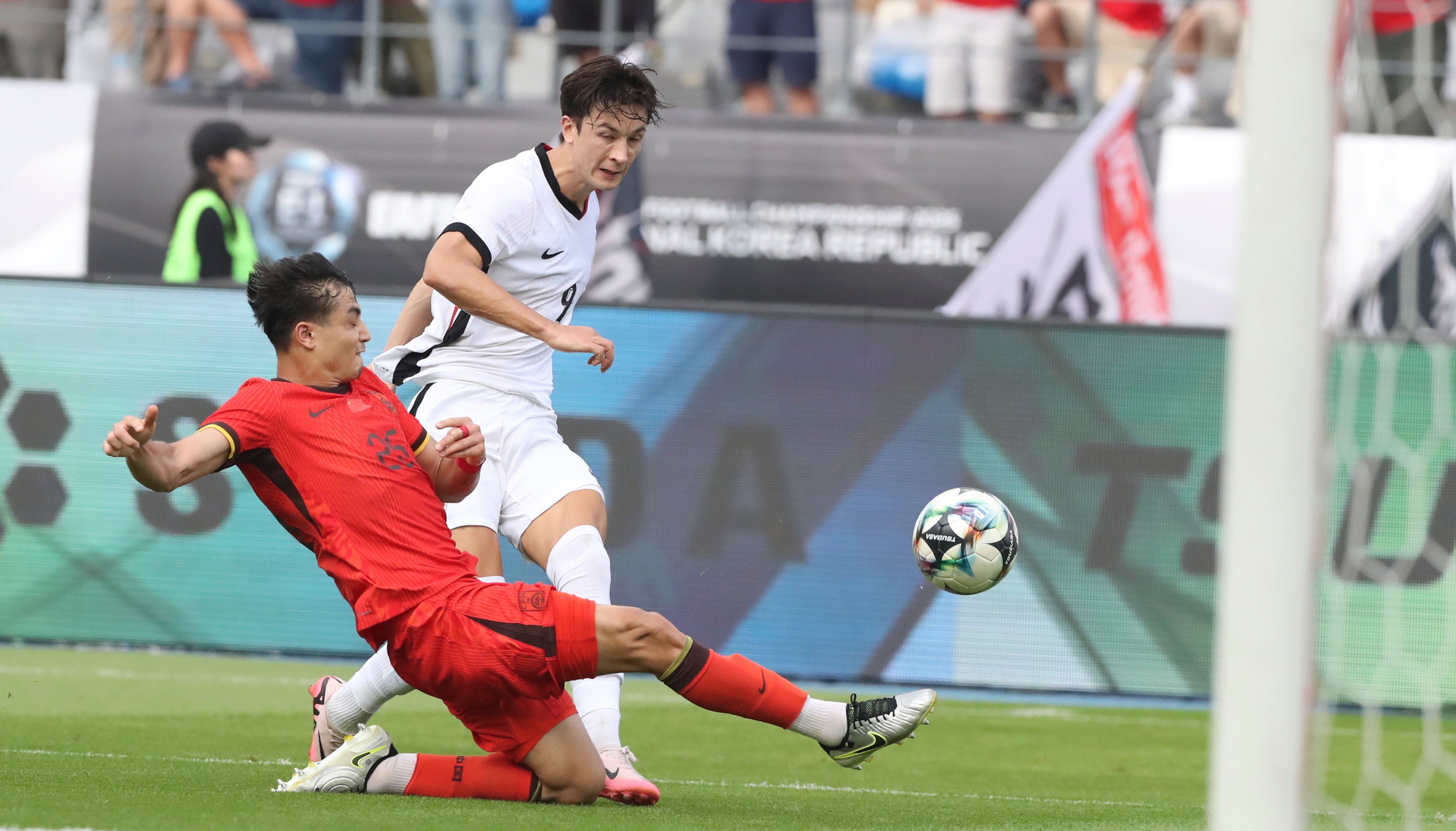 Wumitijiang Yusupu (left) clears the ball away as Matt Orr closes in during Hong Kong’s game against China in the East Asian Football Championship. Photo: Xinhua