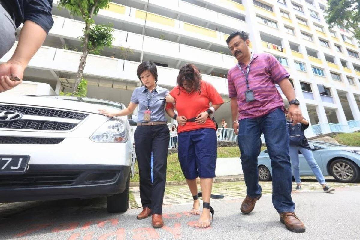 Gaiyathiri Murugayan (centre) is escorted from her Singapore flat in 2016 after the death of her domestic helper. Photo: Today Online