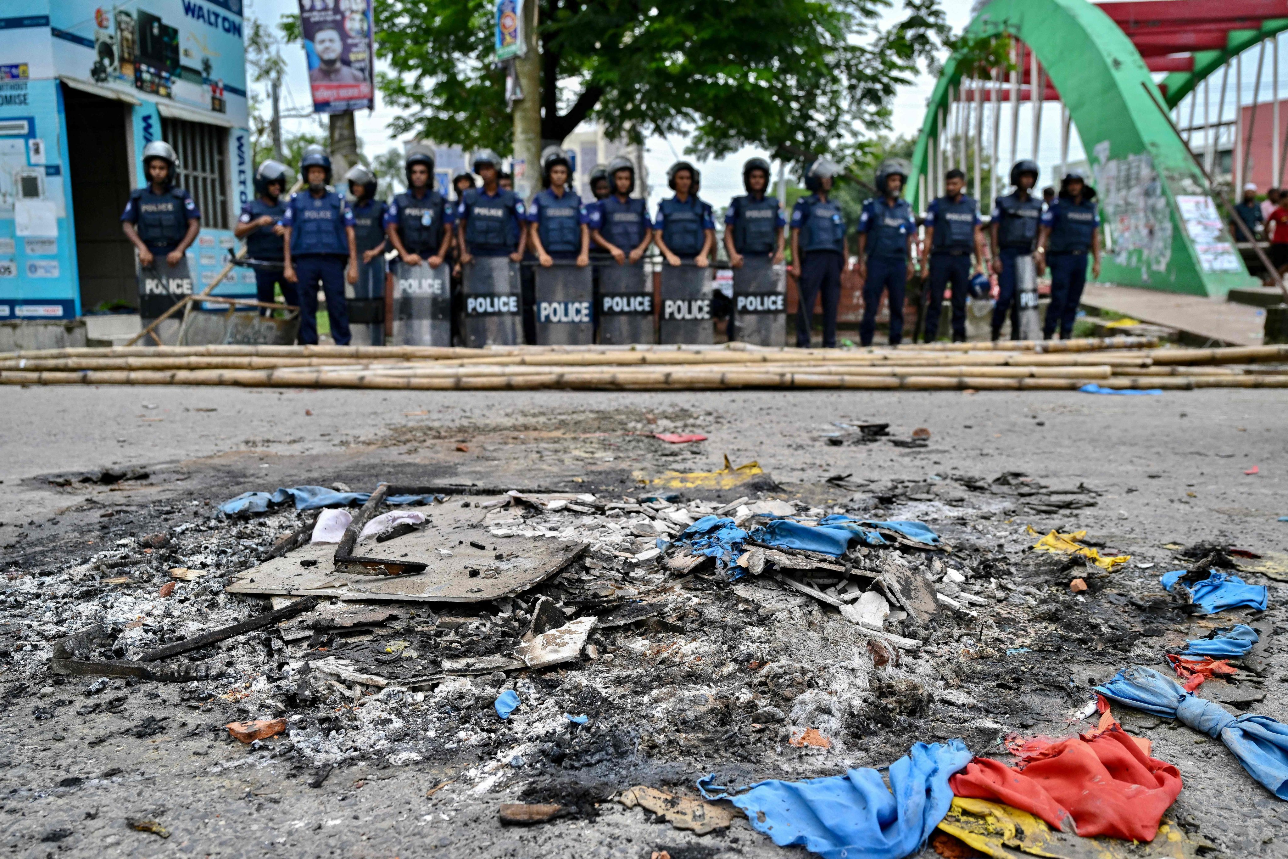 Anti-riot police personnel stand guard near the burnt debris along a street in Gopalganj on Thursday after the clashes during a National Citizens Party rally. Photo: AFP