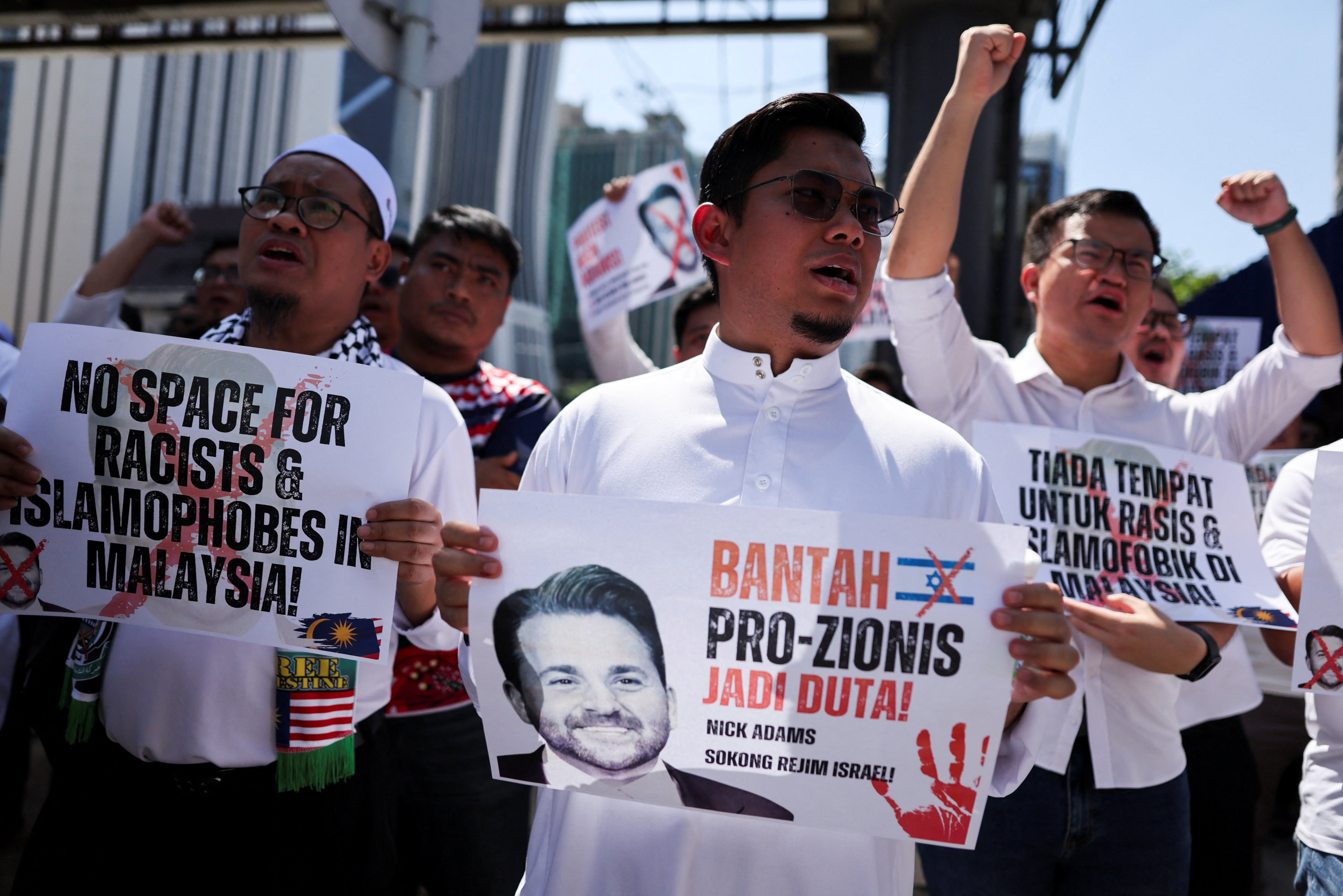 Protesters hold signs and a picture of US envoy pick Nick Adams outside the US embassy in Kuala Lumpur on Friday. Photo: Reuters