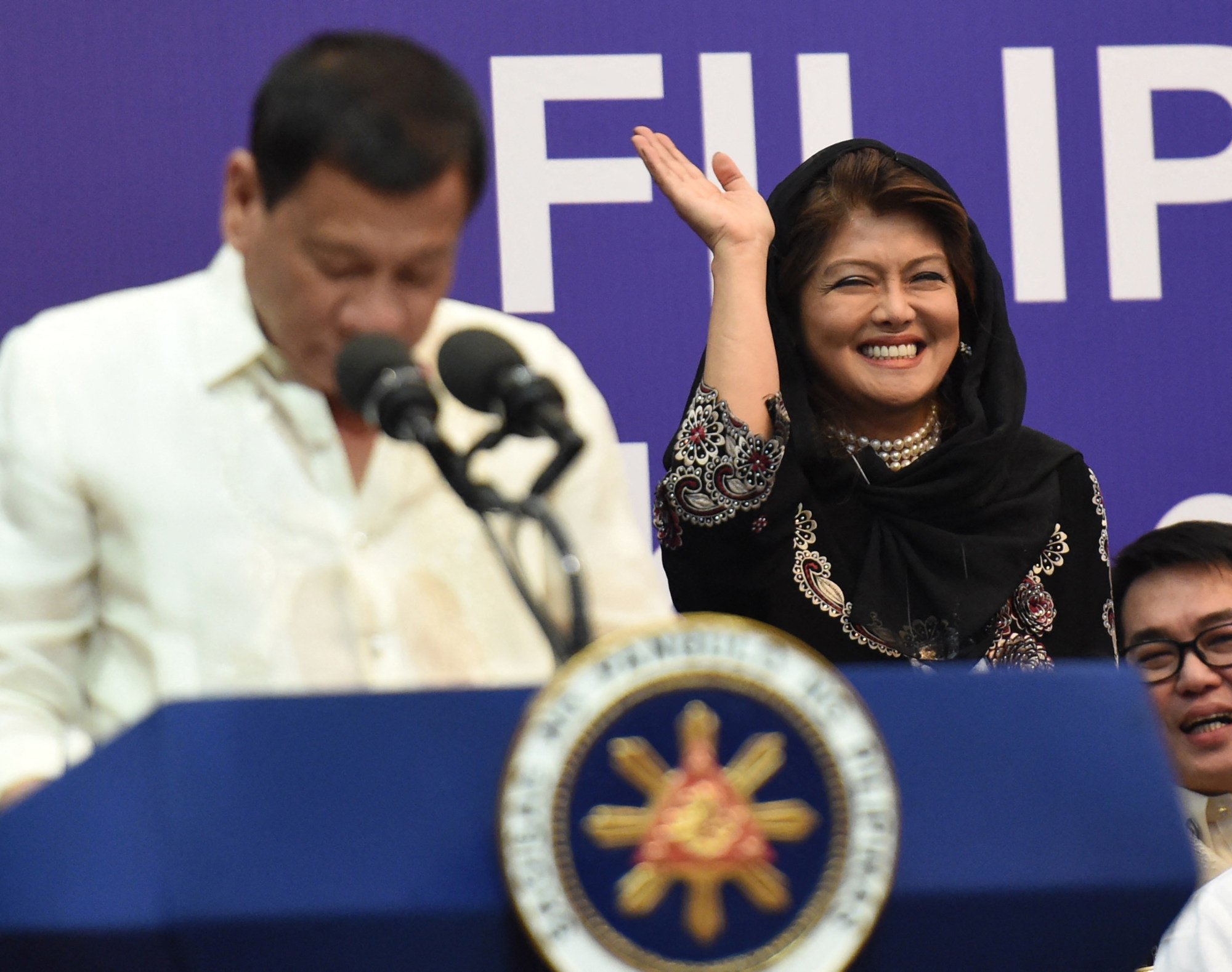 Imee Marcos waves as then president Rodrigo Duterte speaks during a meeting with the Filipino community in Riyadh, Saudi Arabia, in 2017. Photo: AFP