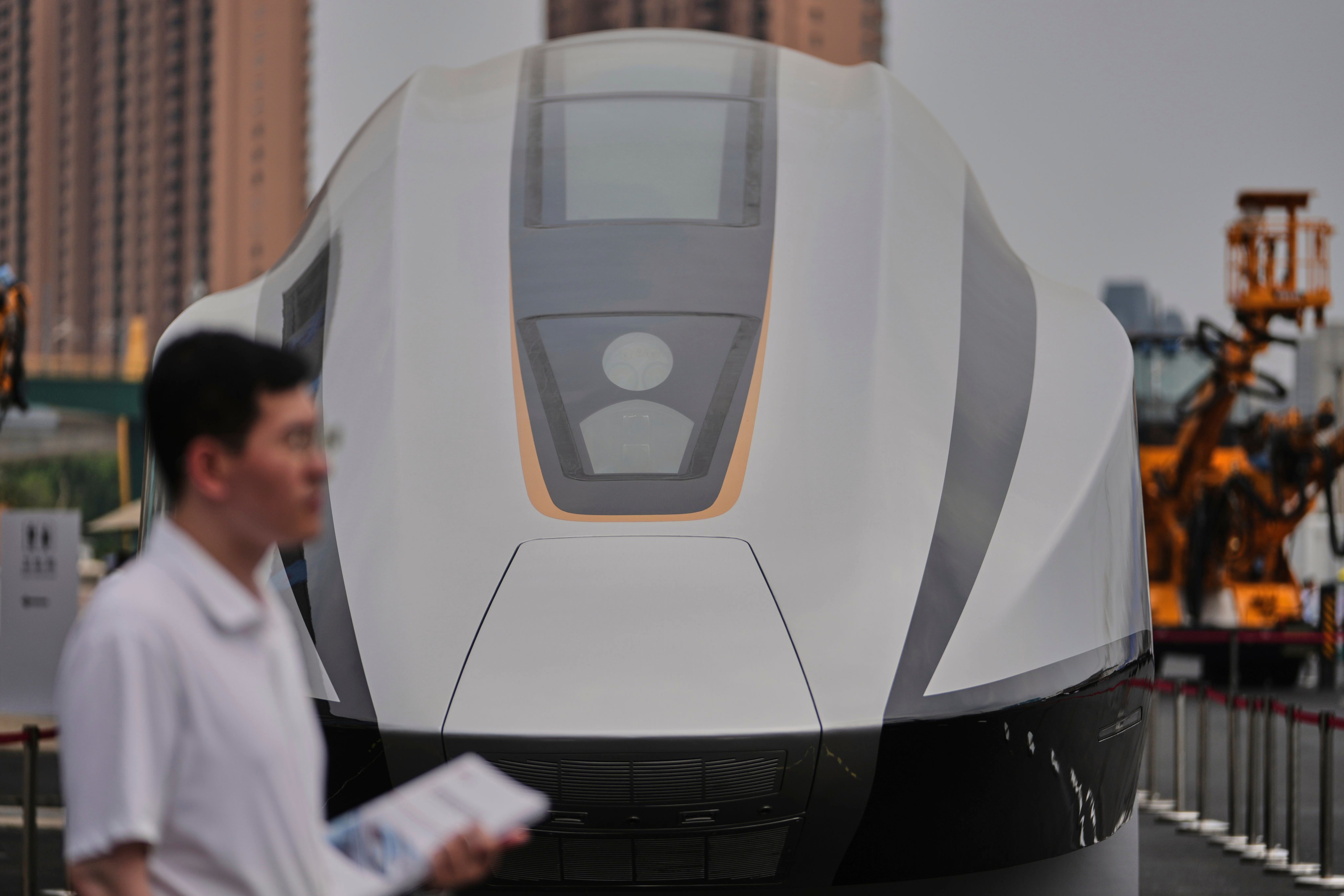 A volunteer holds leaflets as he stands near a 600km High Speed Maglev model showcasing at the National Railway Test Center during a tour by delegates to the World Congress on High-Speed Rail held in Beijing, Wednesday, July 9, 2025. Photo: AP