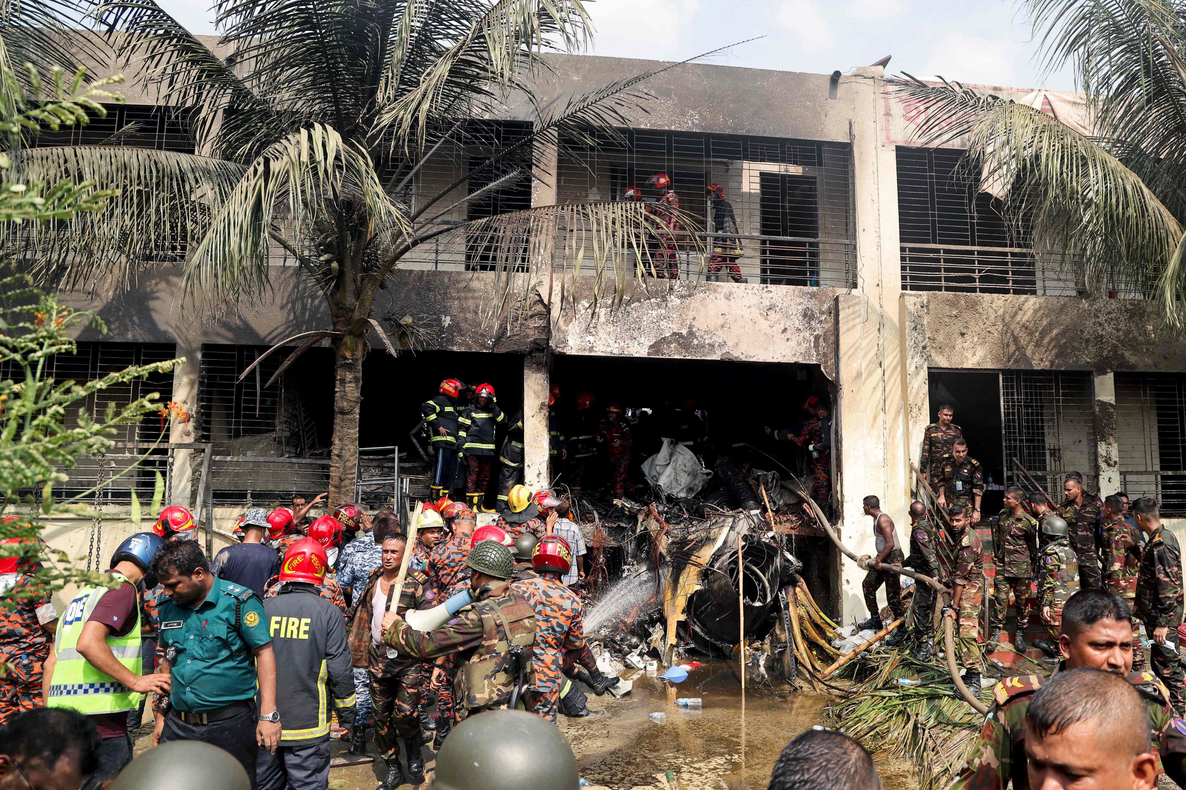 Bangladesh’s fire service and security personnel conduct a search and rescue operation after an Air Force training jet crashed into a school in Dhaka on Monday. Photo: AFP