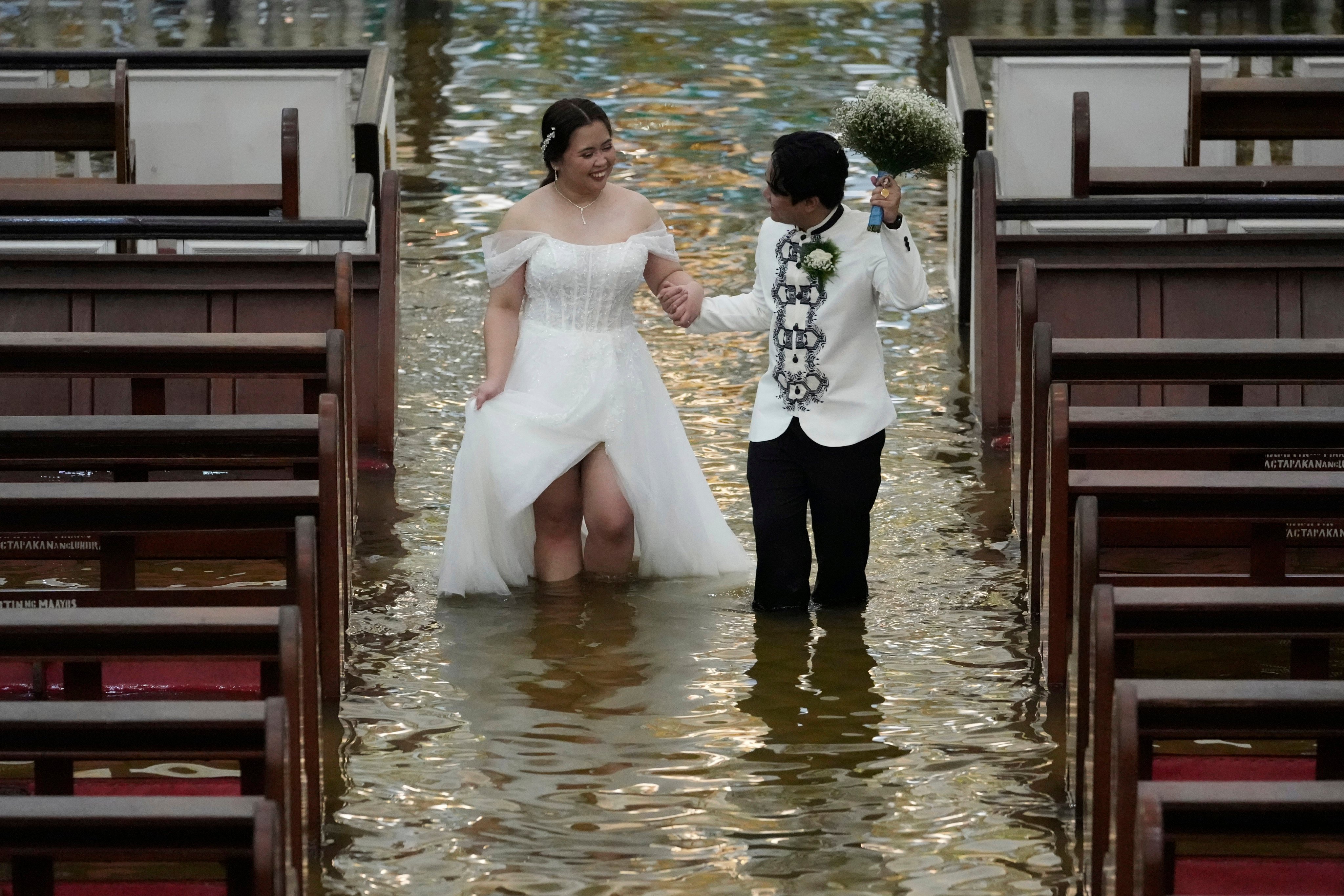 Newlyweds Jade Rick Verdillo (right) and Jamaica walk hand in hand during their wedding in a flooded church in the Philippines. Photo: AP