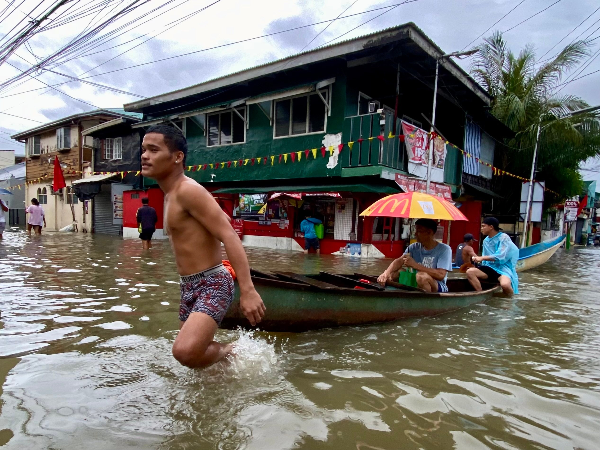 People make their way through floodwaters on a wooden boat the town of Kawit, Cavite province, Philippines, on Thursday. Photo: EPA