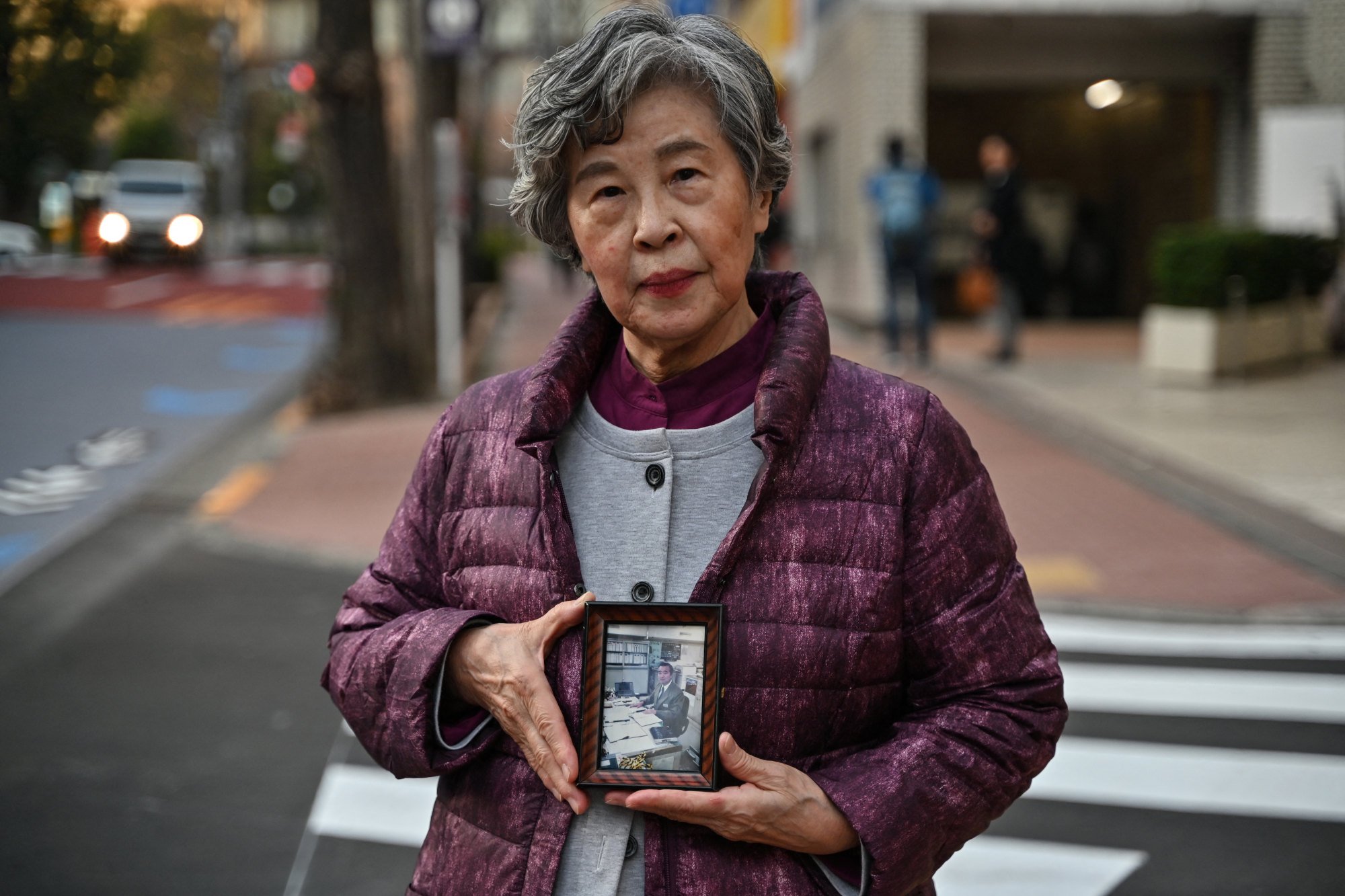 Shizue Takahashi, whose husband Kazumasa Takahashi was killed in the sarin gas attack in 1995, holds his photo outside a subway station in Tokyo in February. Photo: AFP