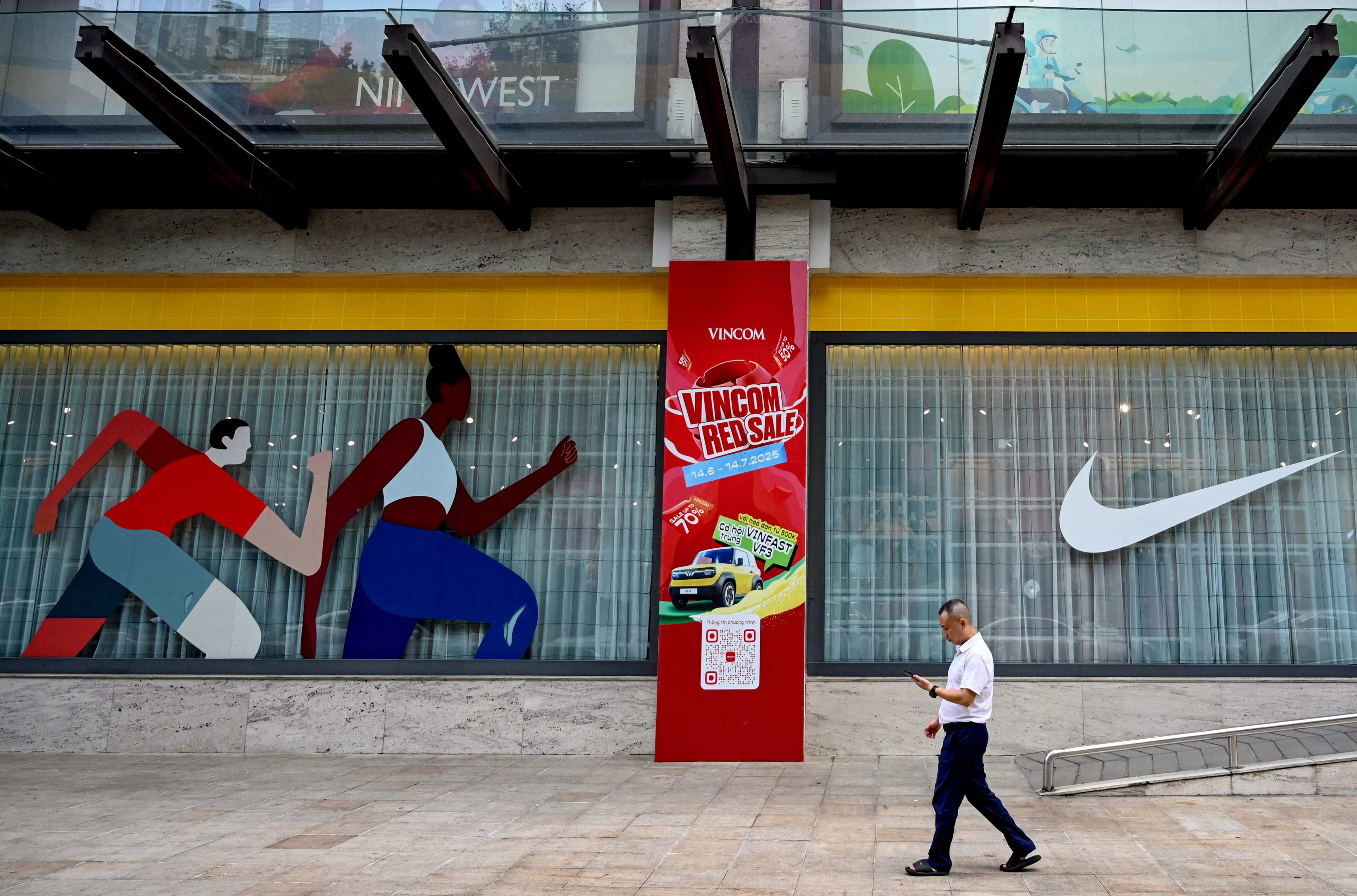 A man walks past a Nike advert outside a shopping centre in Hanoi on July 8. Vietnam has apparently managed to get its initial tariff rate more than halved. Photo: AFP