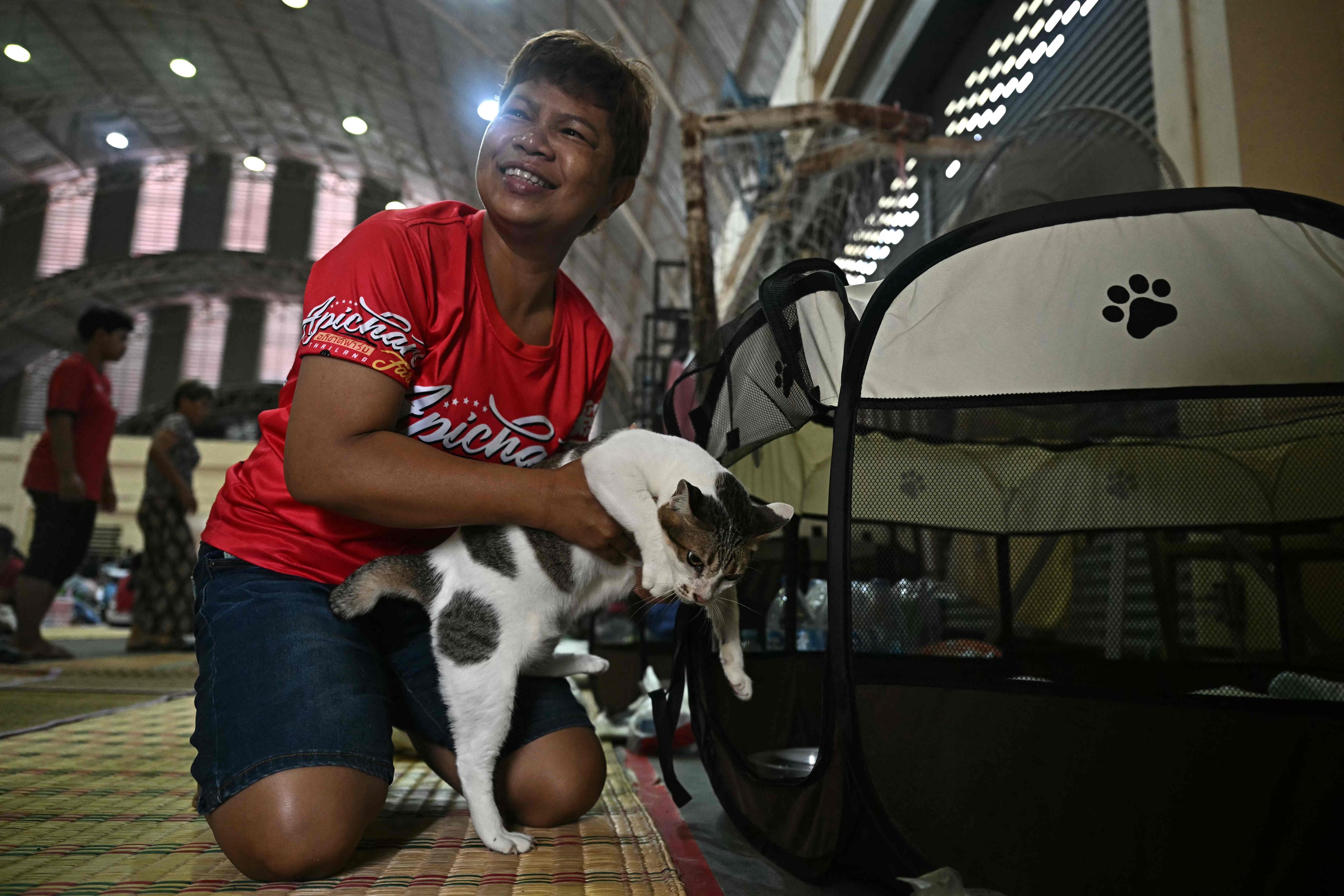 Pornpan Sooksai holds one of her cats as they take shelter in a gymnasium amid fighting between Thailand and Cambodia. Photo: AFP