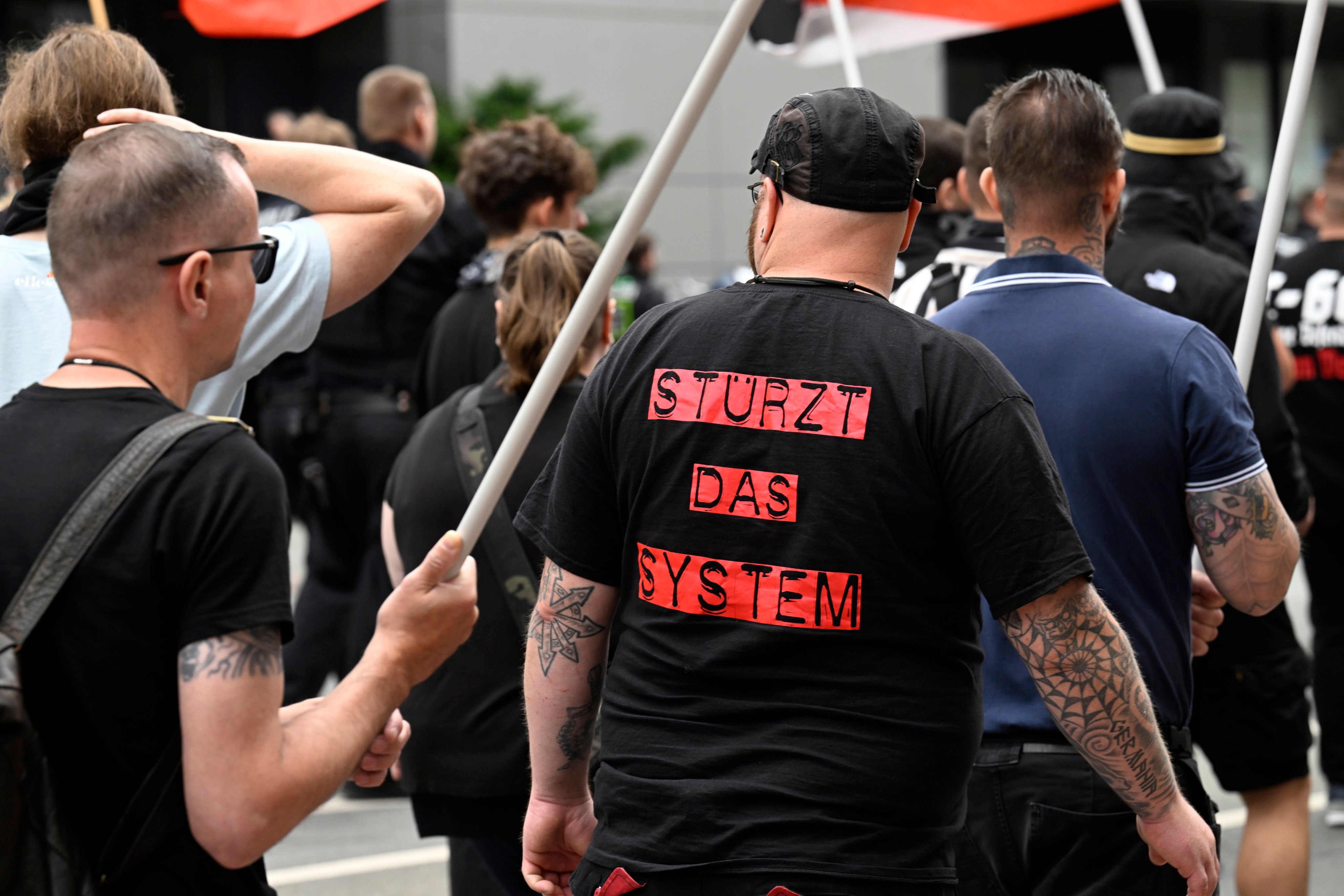A far-right demonstrator wearing a t-shirt that reads “topple the system” protests in Germany. Photo: dpa