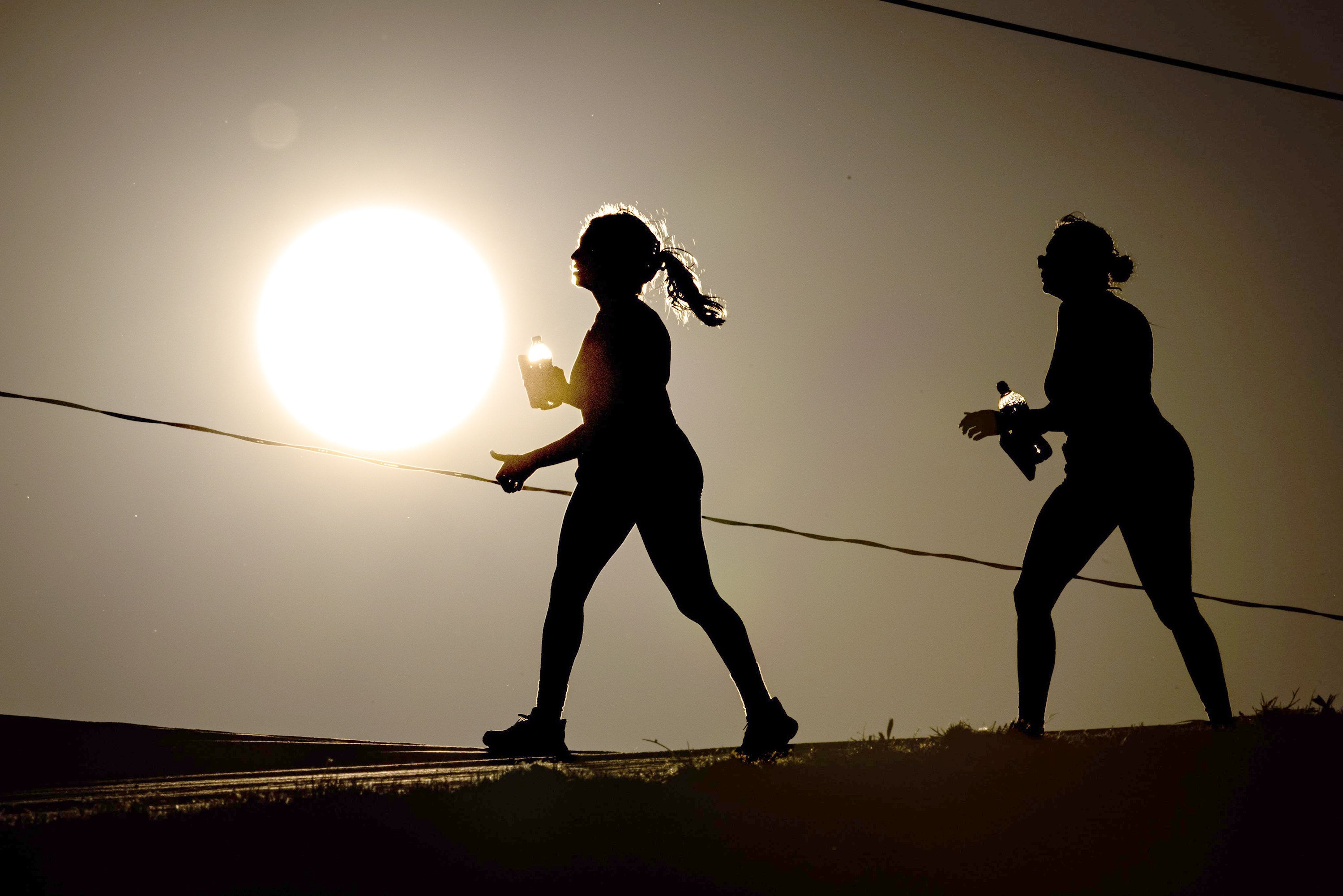Pedestrians carry water while walking in Dallas on Friday. Photo: Photo: TNS