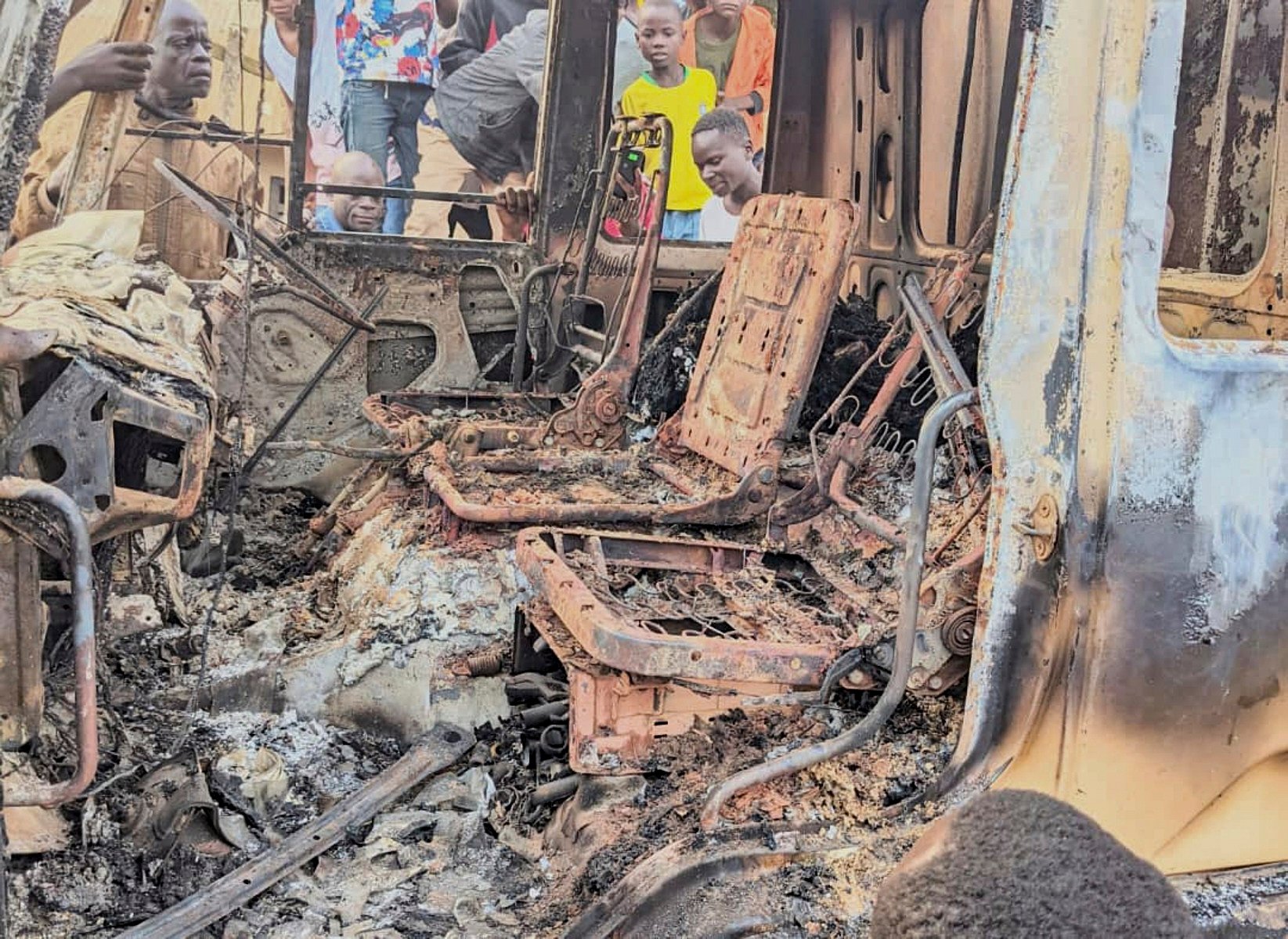 People gather around the charred remains of a burned vehicle following a deadly attack in Komanda, Ituri province of eastern DR Congo on Sunday. Photo: UGC via AP