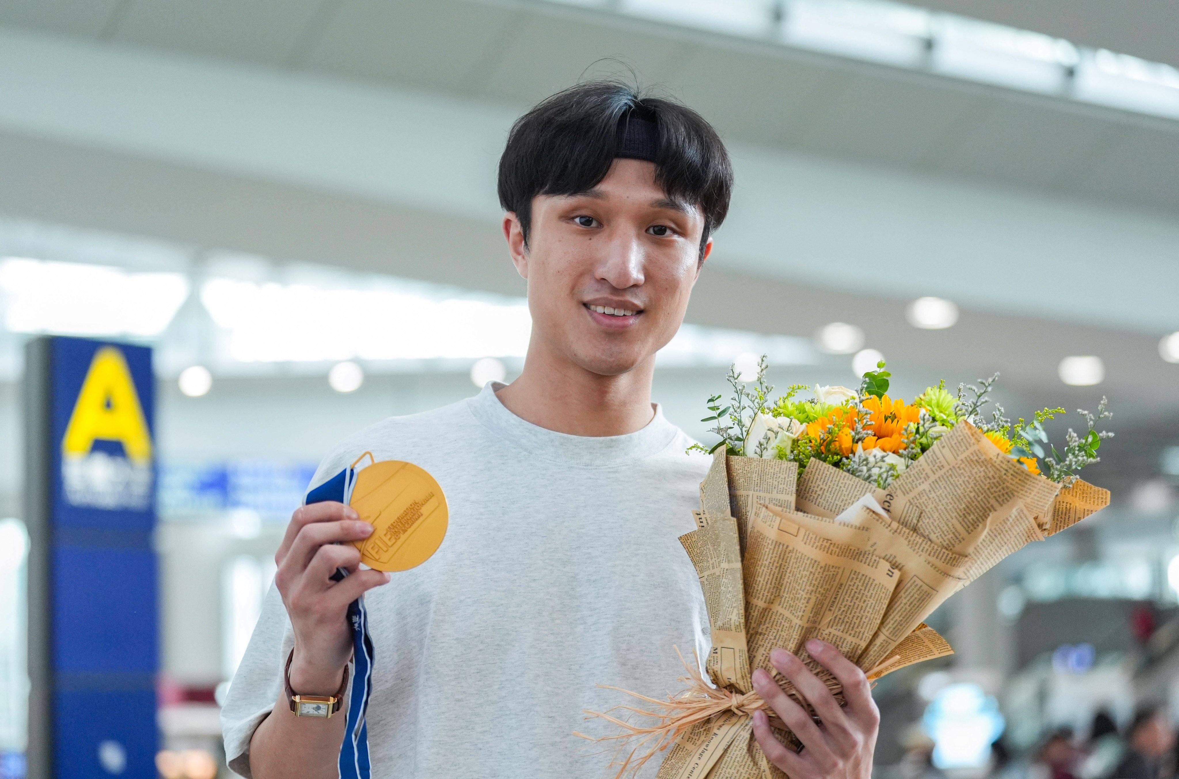 Ryan Choi displays his gold medal on arrival at Hong Kong International Airport on Monday. Photo: Eugene Lee