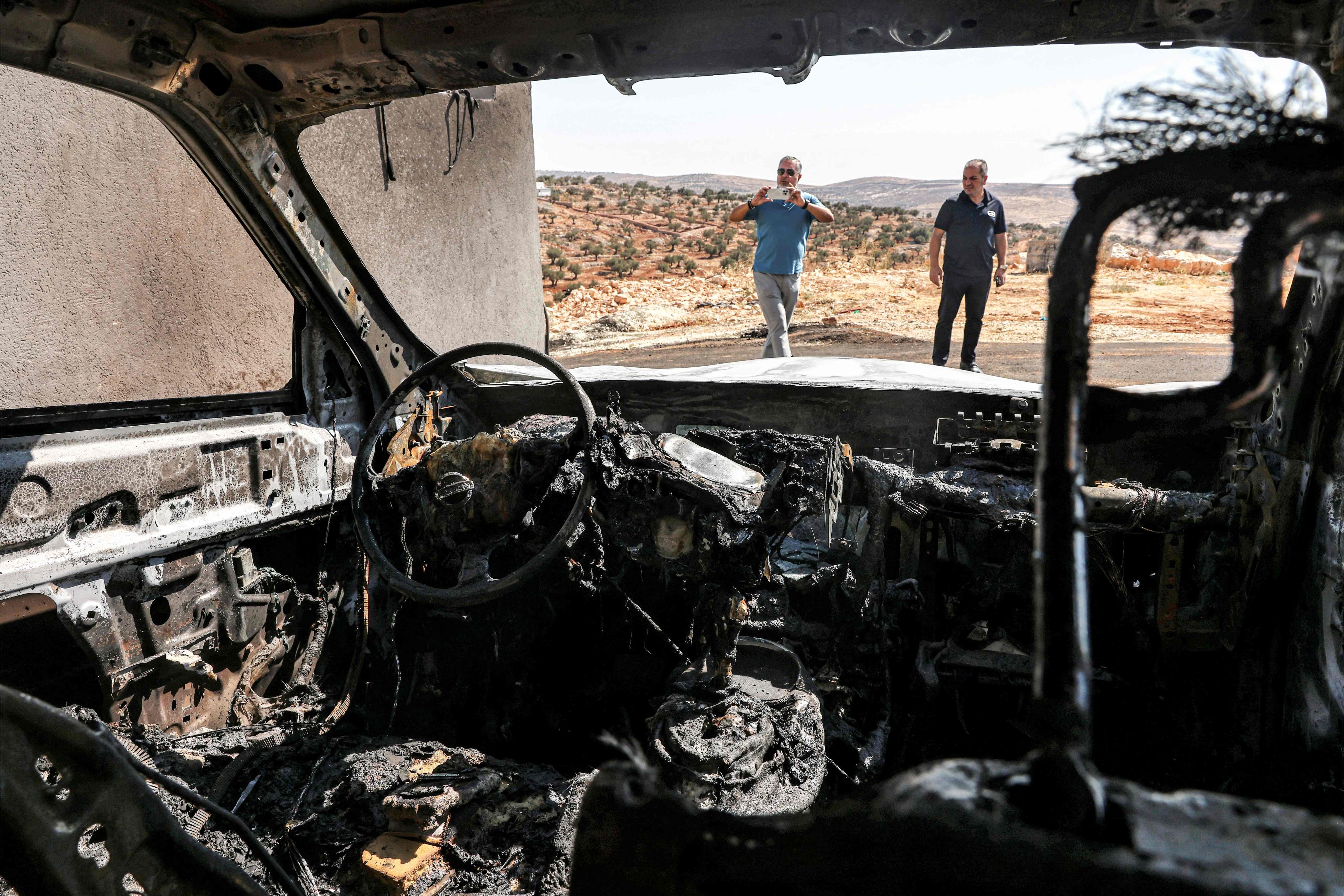 Men stand near a vehicle that was reportedly torched by Israeli settlers during an overnight attack on the Palestinian Christian village of Taybeh, northeast of Ramallah in the occupied West Bank, on Monday. Photo: AFP