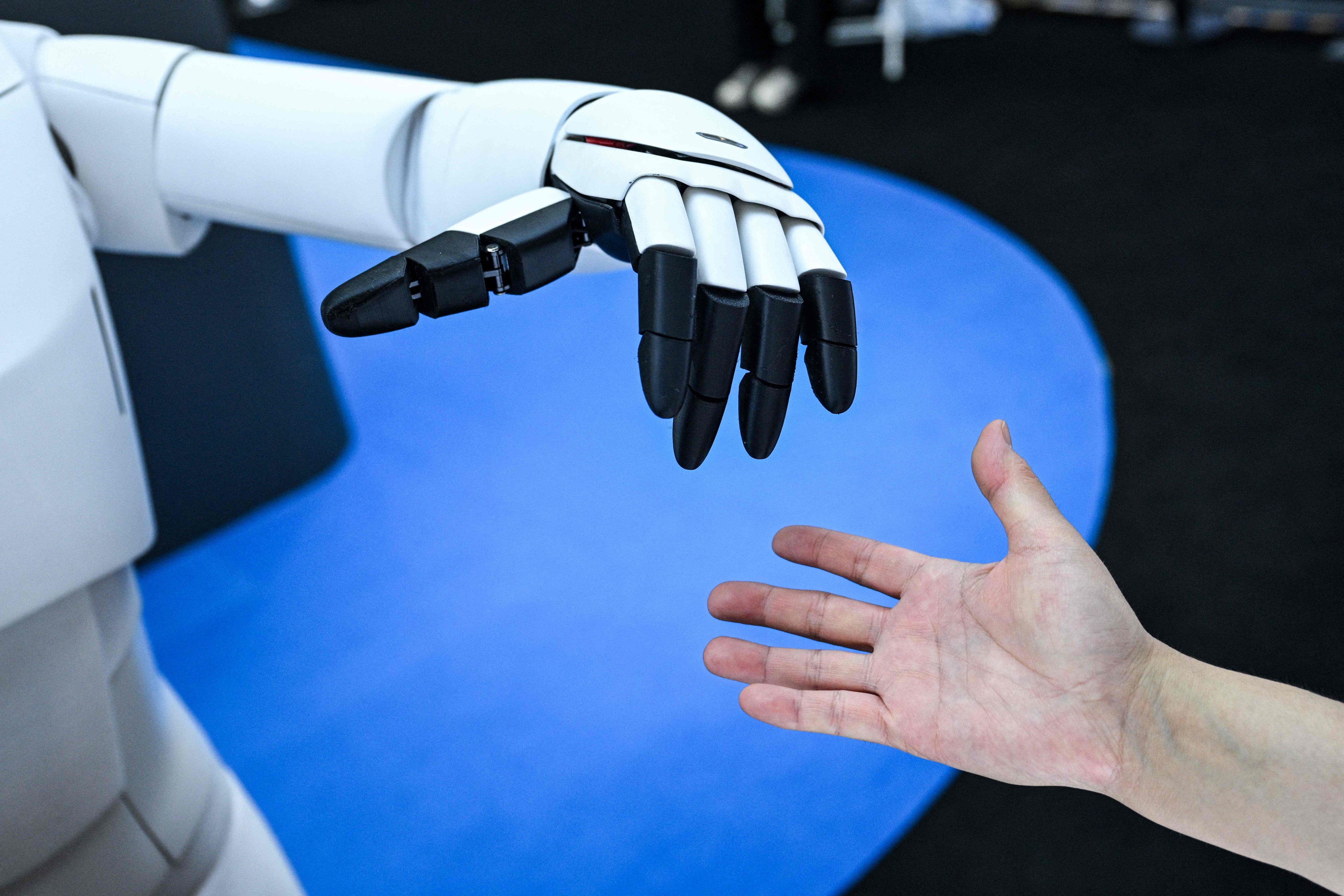 A woman reaches out to touch the hand of a humanoid robot at the World Artificial Intelligence Conference in Shanghai on Monday. Photo: AFP