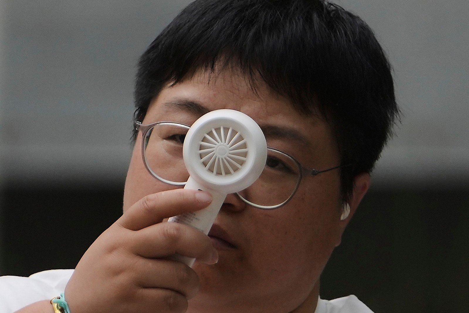 A woman cools herself with a portable electric fan as she rests on a bench on a sweltering day in Beijing. Photo: AP