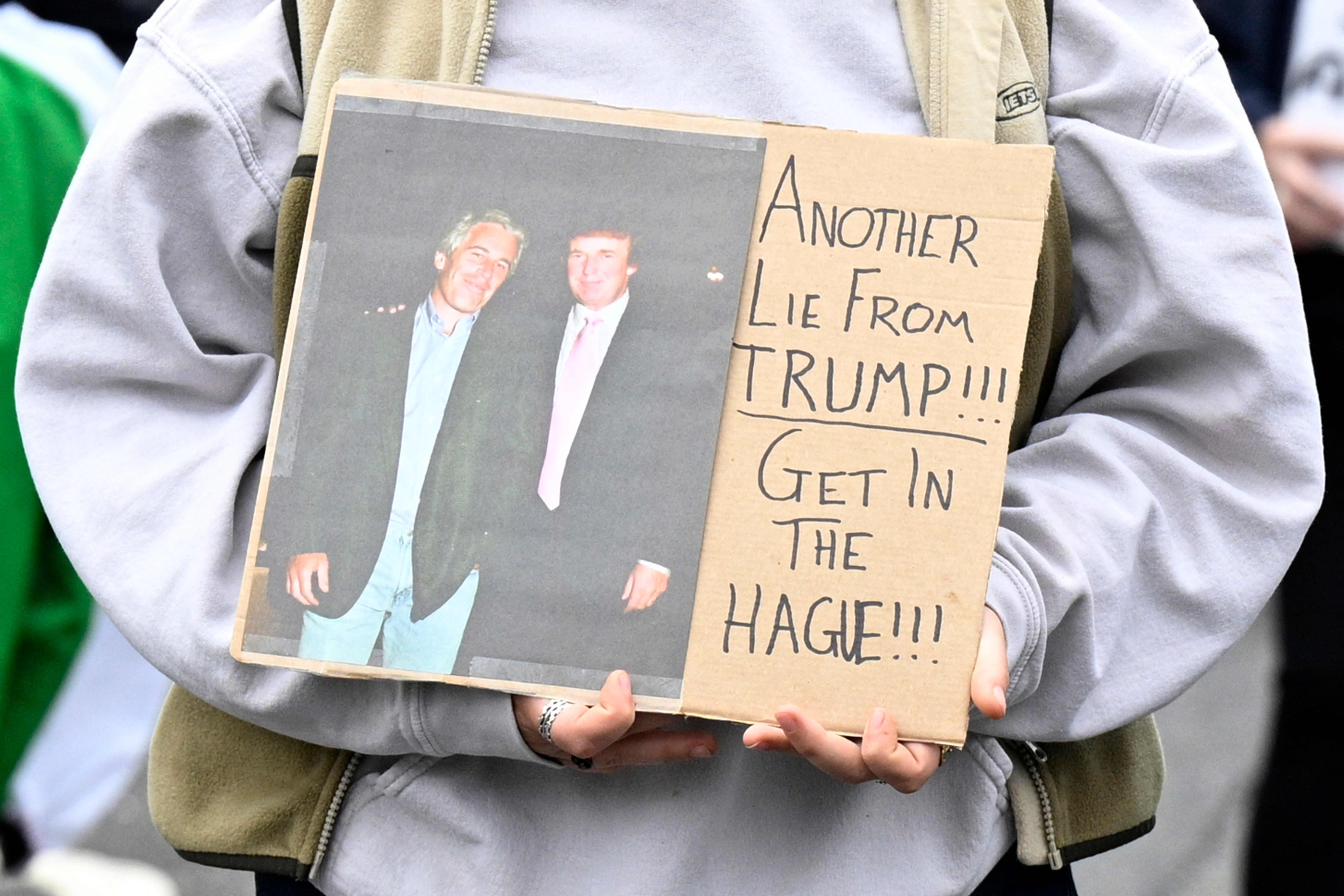 An anti-Trump protester holds a placard showing a photo of US President Donald Trump posing with convicted sex offender Jeffrey Epstein as protesters march at Balmedie, near Trump International Golf Links in Aberdeenshire, Scotland on Monday. Photo: AFP