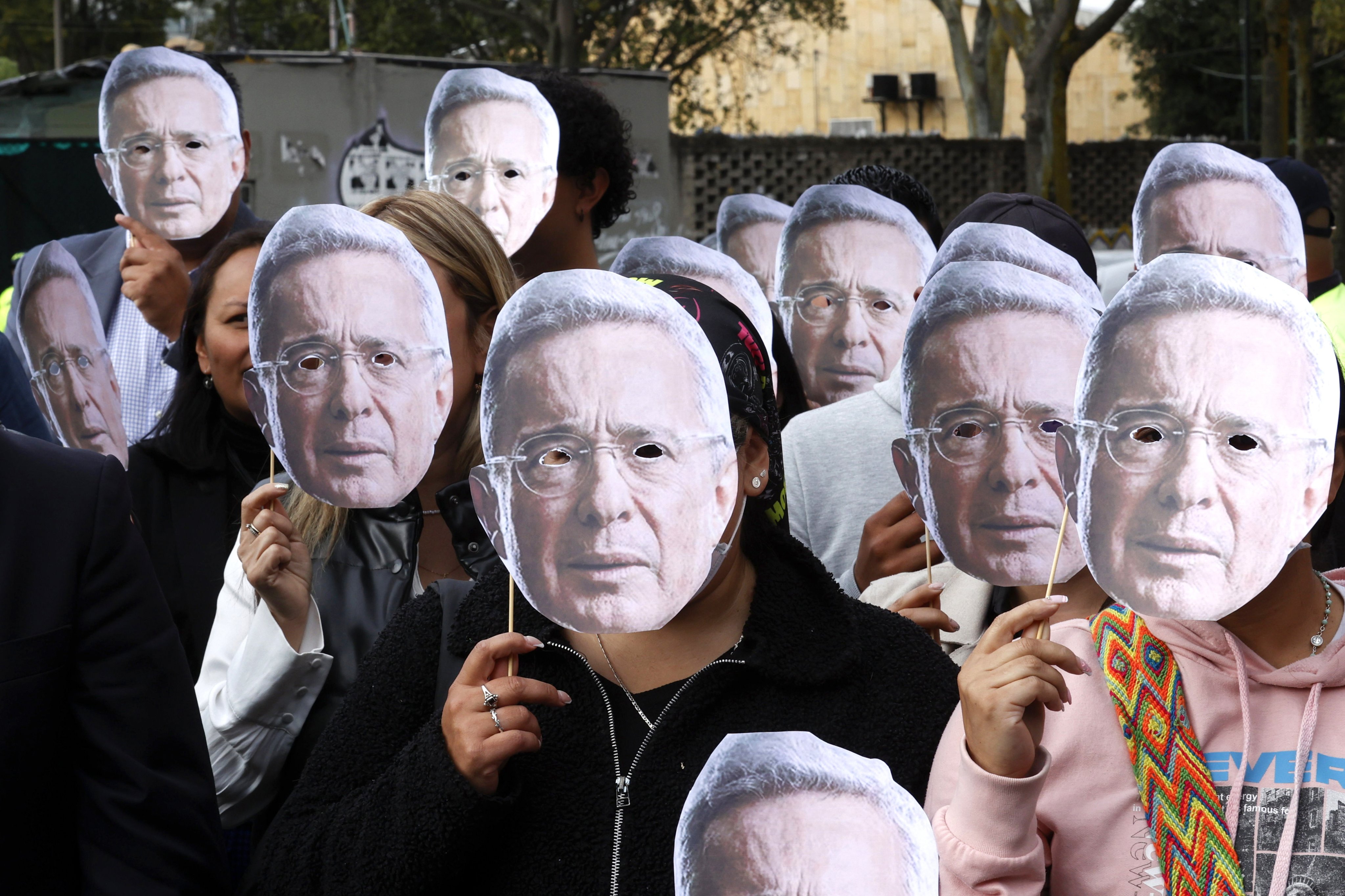 Alvaro Uribe’s supporters wear masks of the former Colombian president as they gather outside the Paloquemao Judicial Complex in Bogota, Colombia, on Monday. Photo: EPA