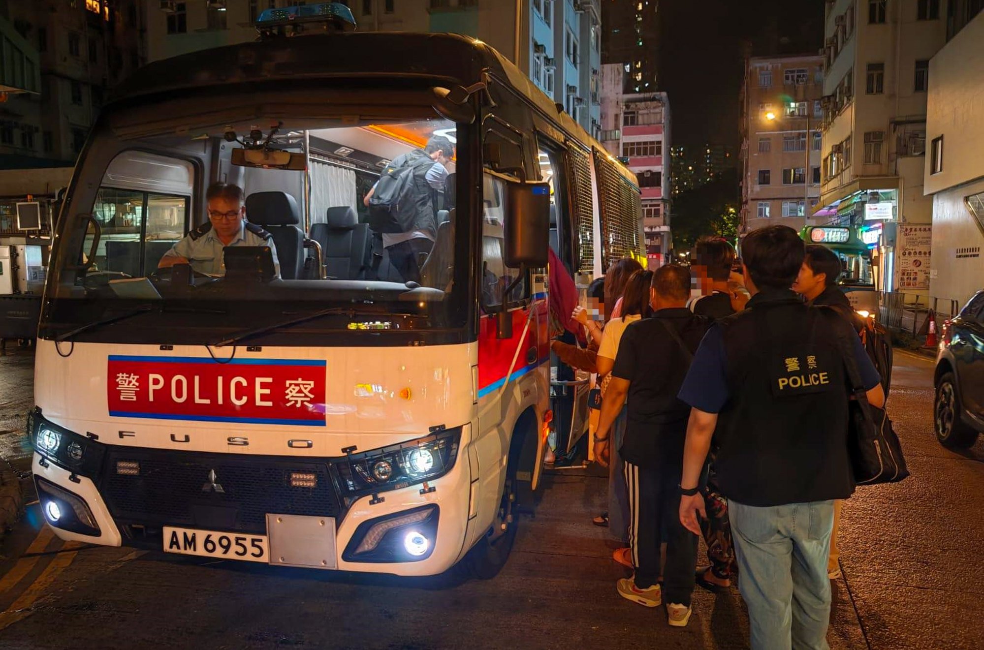 Hong Kong police escort some of the 82 detainees onto a bus. Photo: Handout