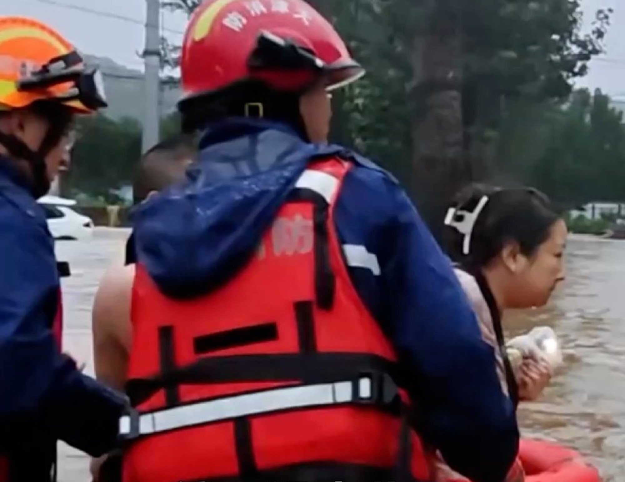 Firefighters carefully usher the man’s wife to a safe place as the floodwater rises. Photo: Handout Firefighters carefully usher the man’s wife to a safe place as the floodwater rises. Photo: Handout