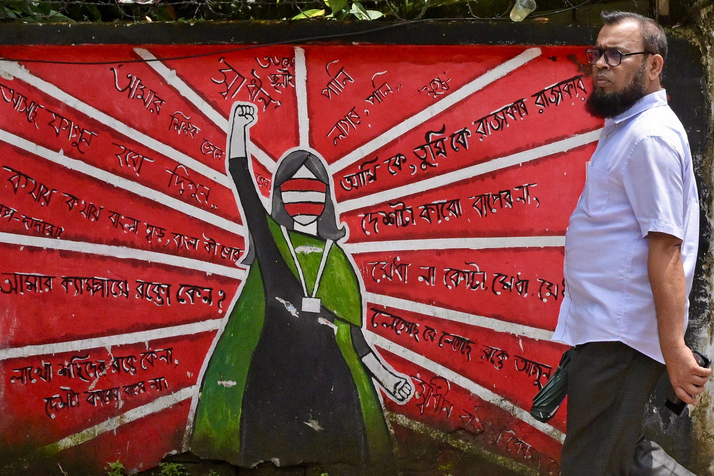 A Bangladeshi man walks past anti-government wall murals along a road in Dhaka. Bangladesh on July 1, 2025, marks one year since students launched protests that culminated weeks later in the overthrow of the government. Photo: AFP