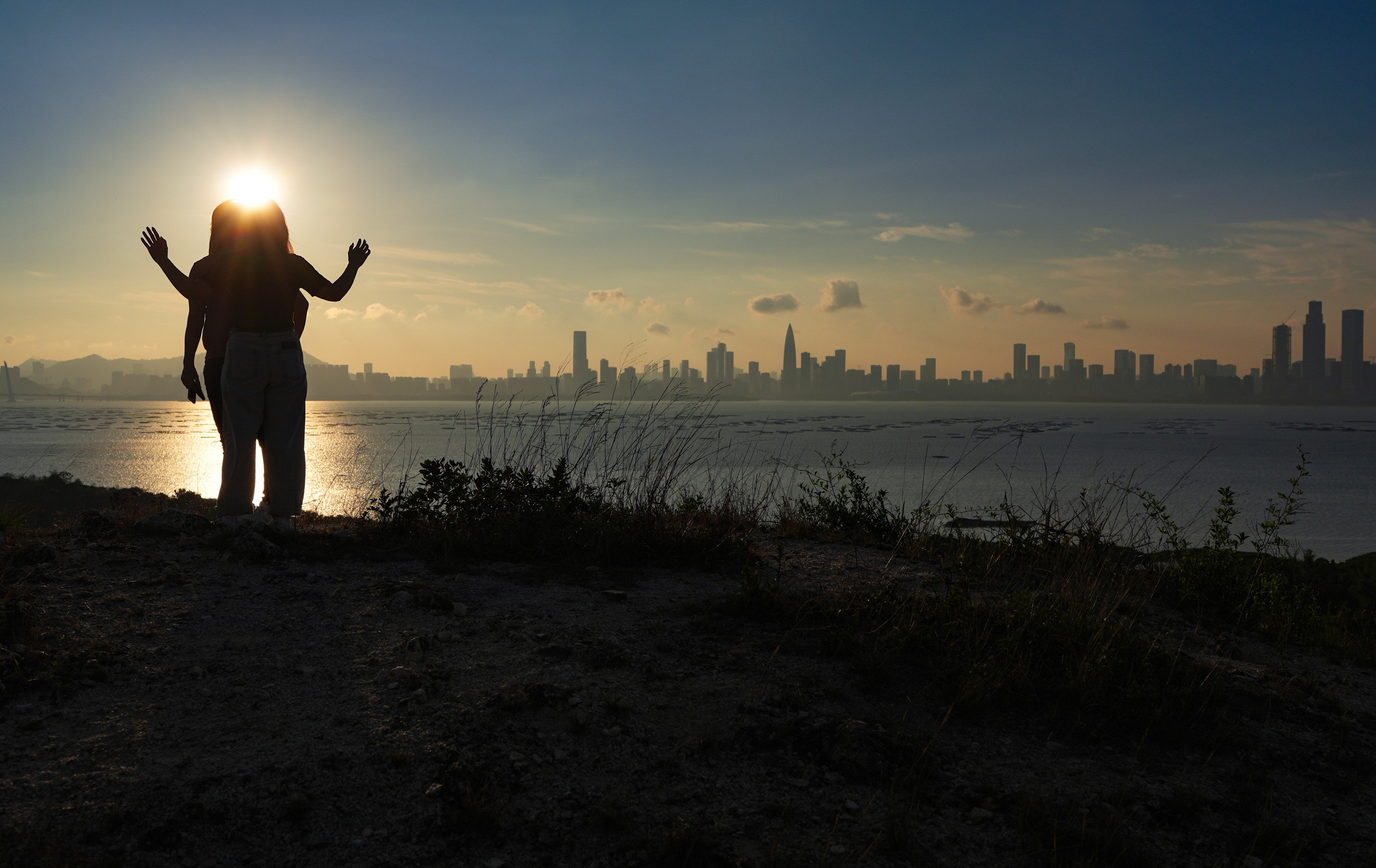Two hikers take in the sunset view of Shenzhen’s skyline from Hong Kong’s Lau Fau Shan on April 21. Photo: Eugene Lee