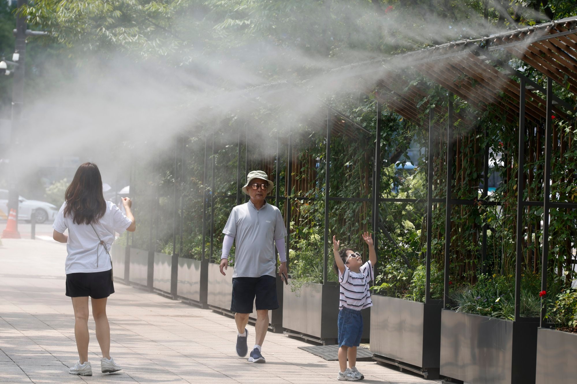 People walk to avoid the hot weather under cooling mists near Seoul City Hall in Seoul on Friday. South Korea is enduring one of its most intense summers in recent memory. Photo: EPA People walk to avoid the hot weather under cooling mists near Seoul City Hall in Seoul on Friday. South Korea is enduring one of its most intense summers in recent memory. Photo: EPA