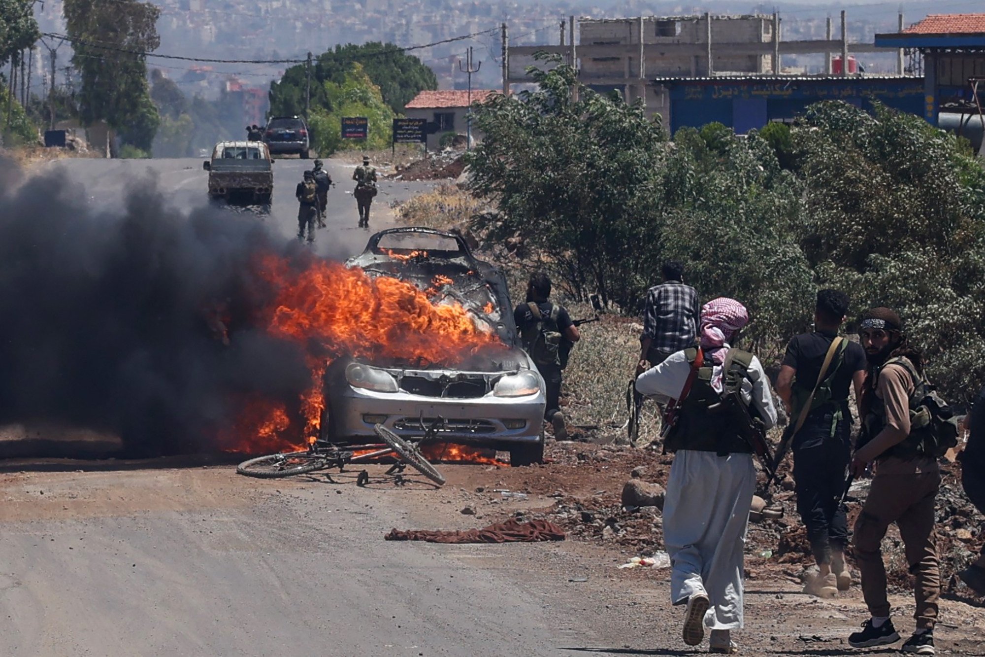 Bedouin and tribal fighters deploy as a car burns at the western entrance of Syria’s Druze heartland of Sweida on July 18. Photo: AFP/Getty Images/TNS