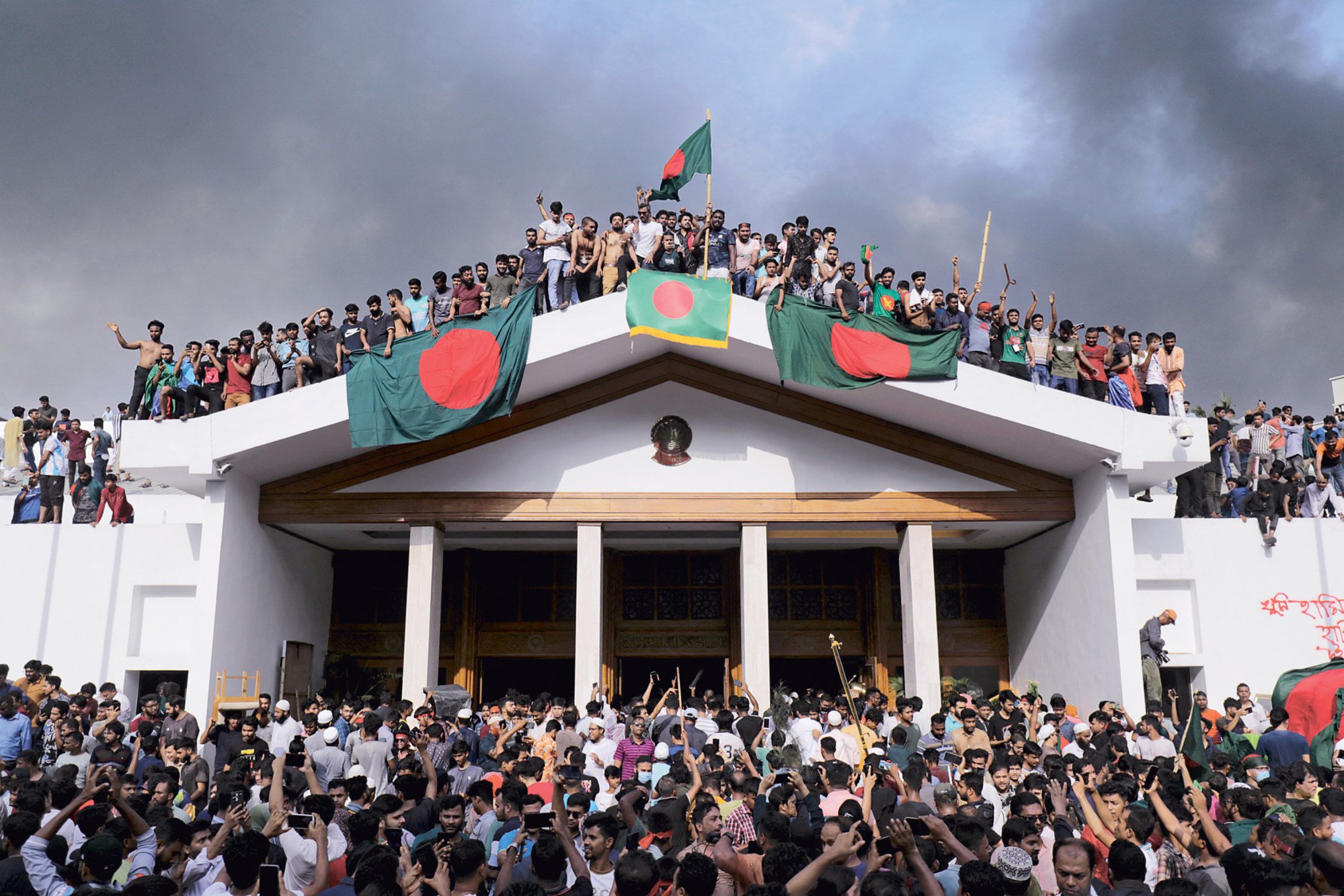 Anti-government protestors display Bangladesh’s national flag as they storm Prime Minister Sheikh Hasina’s palace in Dhaka on August 5. Photo: TNS