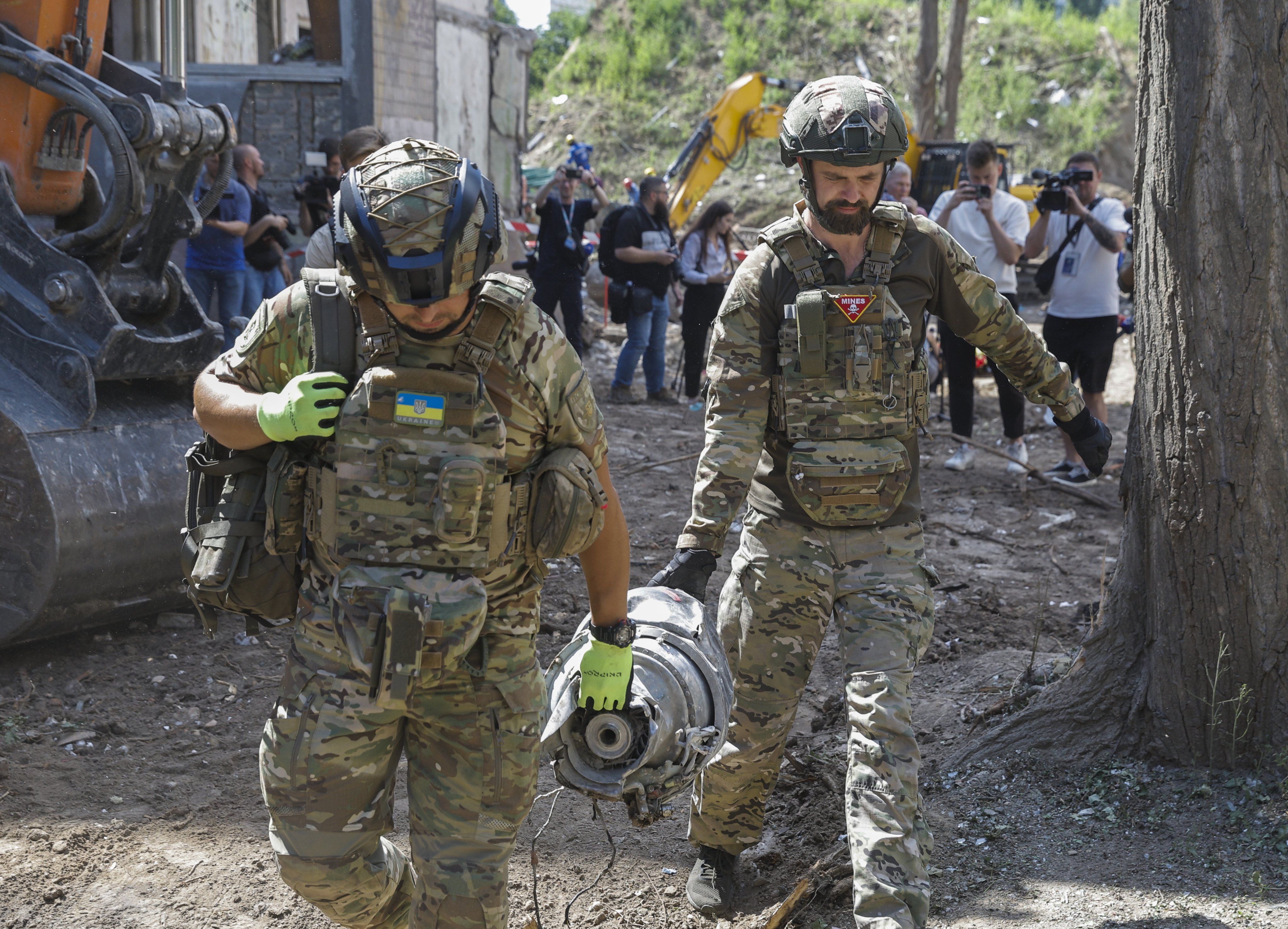 Experts carry a part of the rocket on Friday at the site of a rocket strike on a building in Kyiv. Photo: EPA