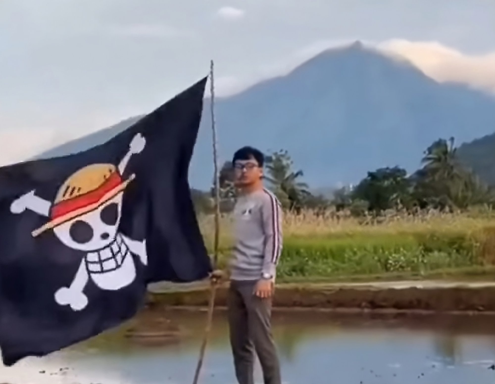 A man in Indonesia holds a One Piece flag with an active volcano in the background. Photo: Facebook A man in Indonesia holds a One Piece flag with an active volcano in the background. Photo: Facebook