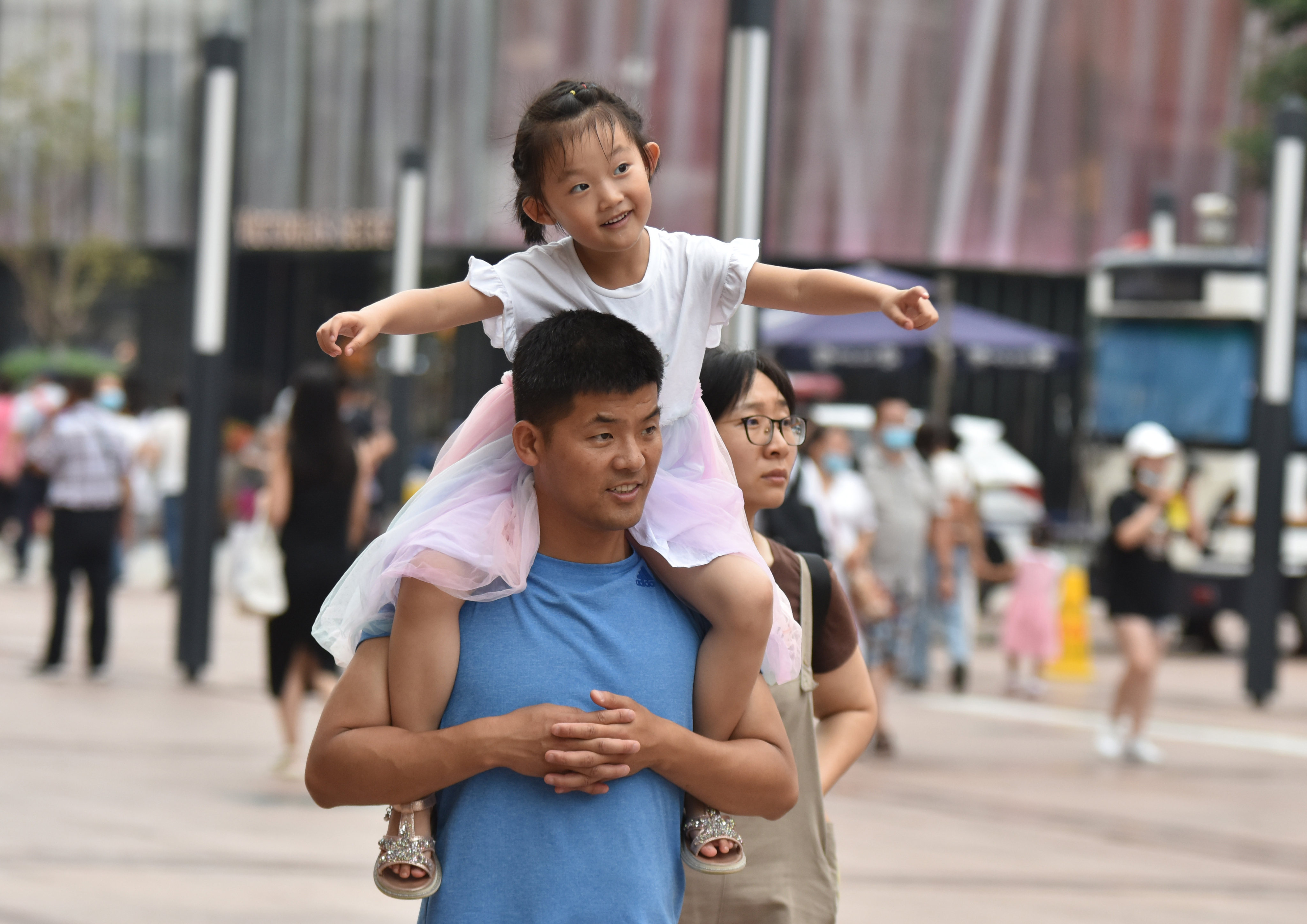 A father carries his daughter on his shoulders on Wangfujing Commercial Street in Beijing, July 21, 2021. Photo: SOPA Images/LightRocket via Getty Images