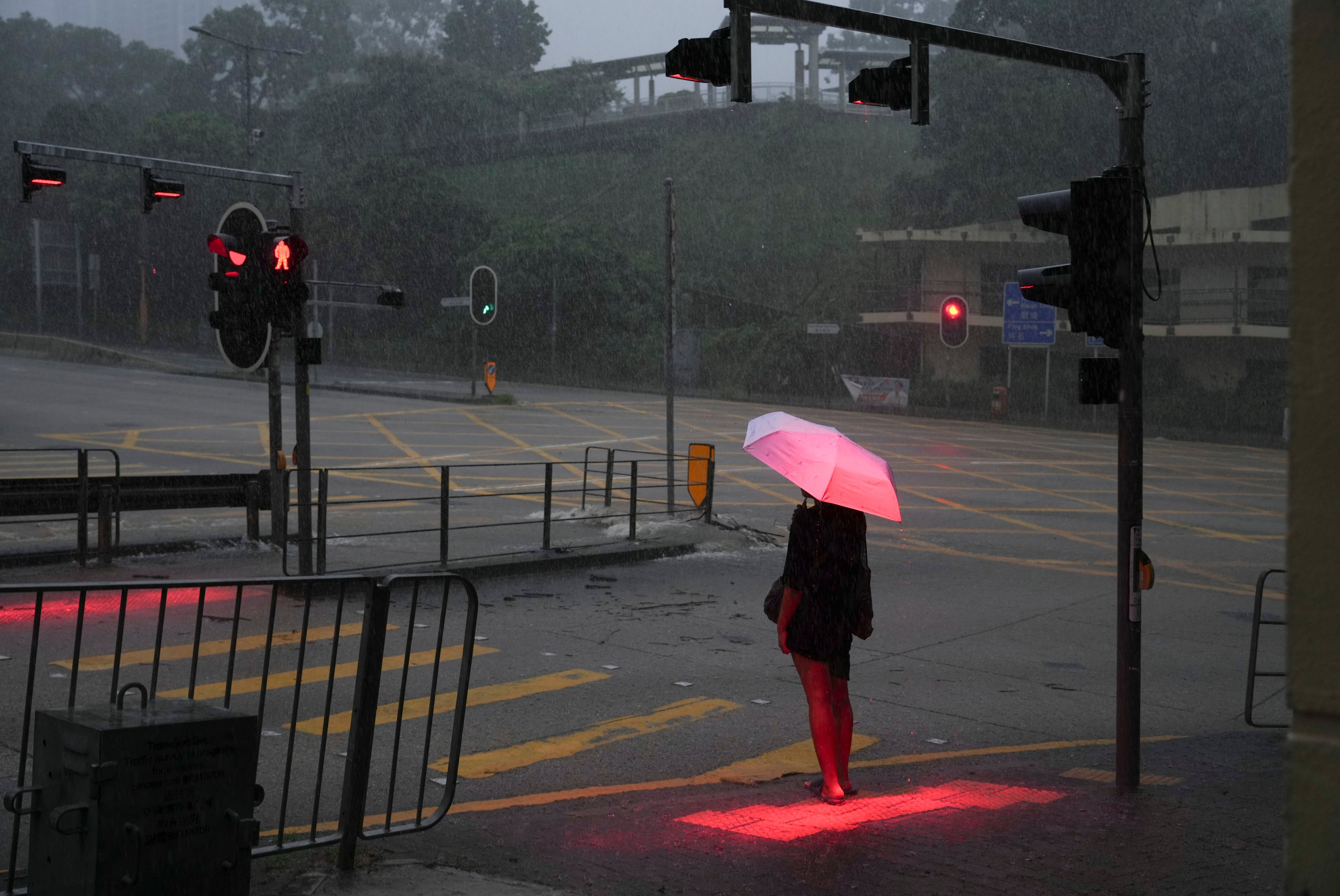 A woman waits to cross a flooded section of New Clear Water Bay Road in Choi Hung on August 5. The Hong Kong Observatory had issued a black rainstorm warning for the second time in six hours. Photo: Sam Tsang