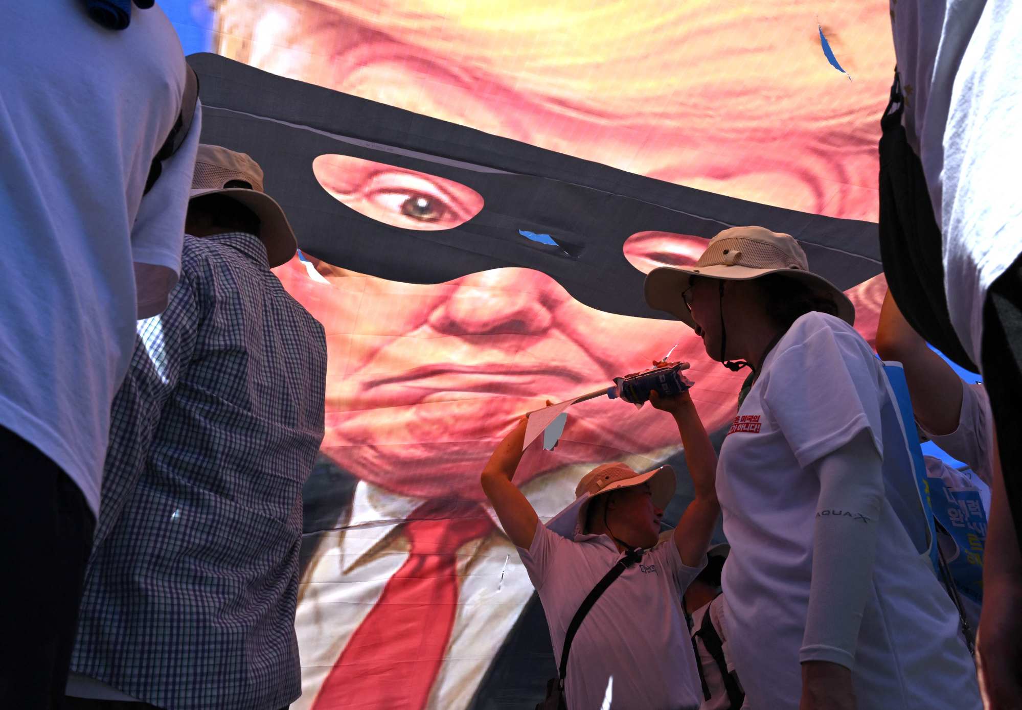 South Korean protesters tear a banner showing a caricature of US President Donald Trump as a robber during a rally in Seoul against Washington’s tariff policy on July 27. Photo: AFP South Korean protesters tear a banner showing a caricature of US President Donald Trump as a robber during a rally in Seoul against Washington’s tariff policy on July 27. Photo: AFP