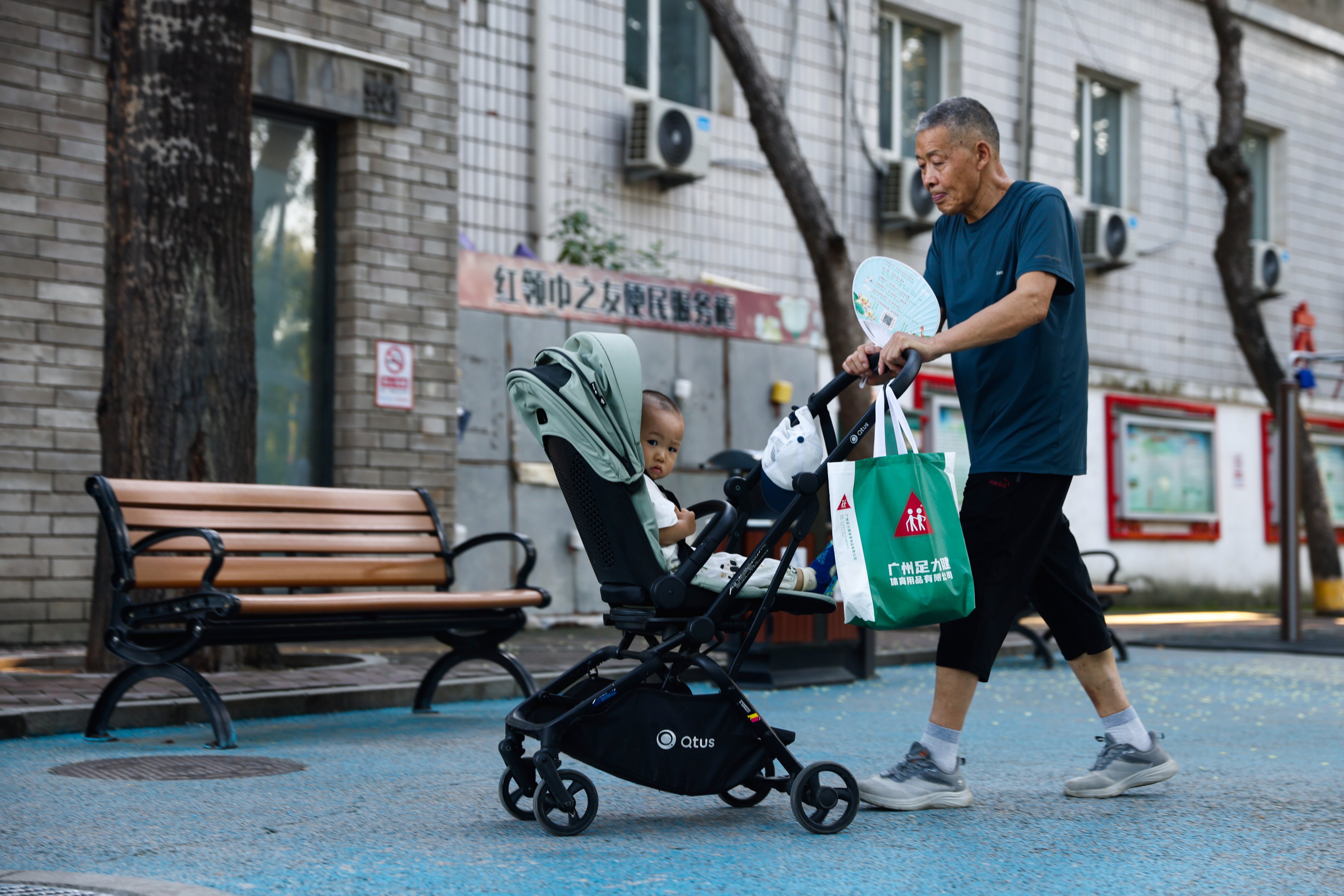 An elderly man pushes a stroller with a child in a park in Beijing on July 30.China’s Ministry of Finance has announced that it will allocate 90 billion yuan (US$12.5 billion) for the initial budget of childcare subsidy payments in 2025. Photo: EPA