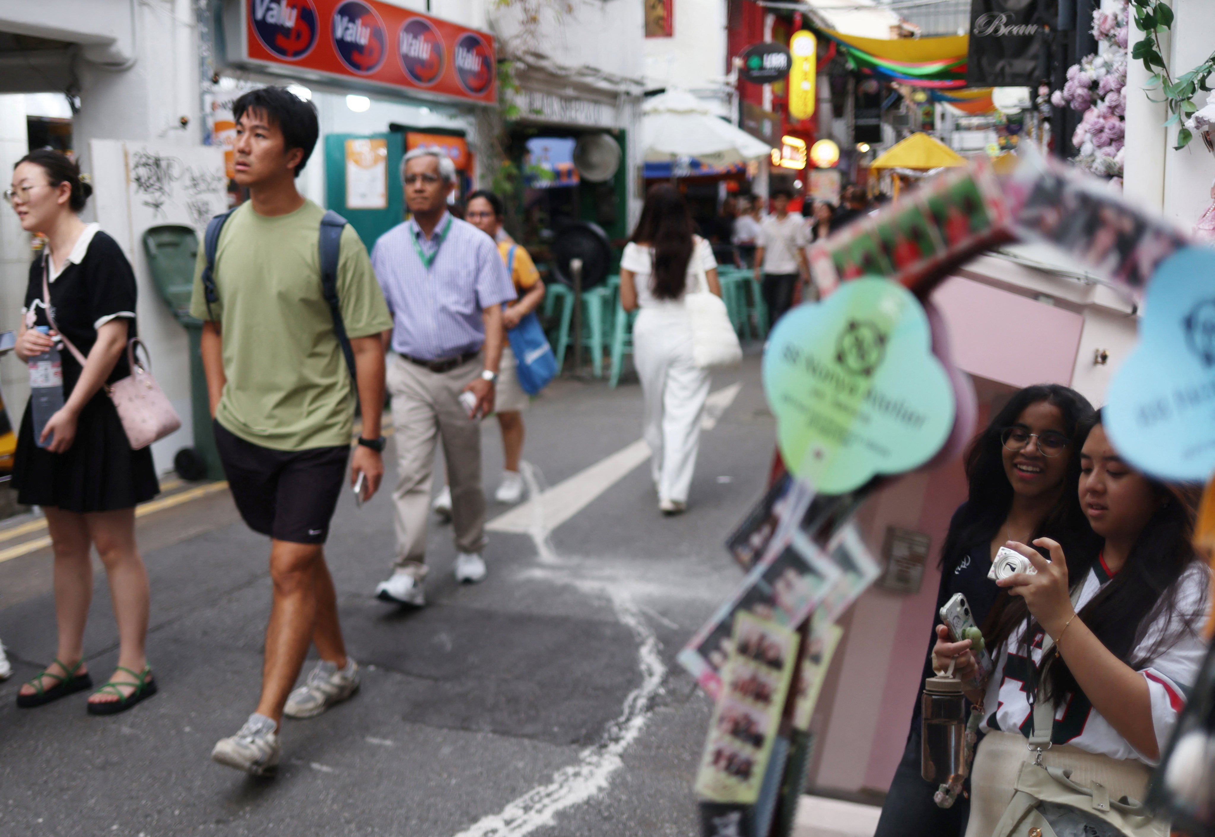 Young people take photos along a shopping street in Kampong Glam district in Singapore on June 11. Photo: Reuters