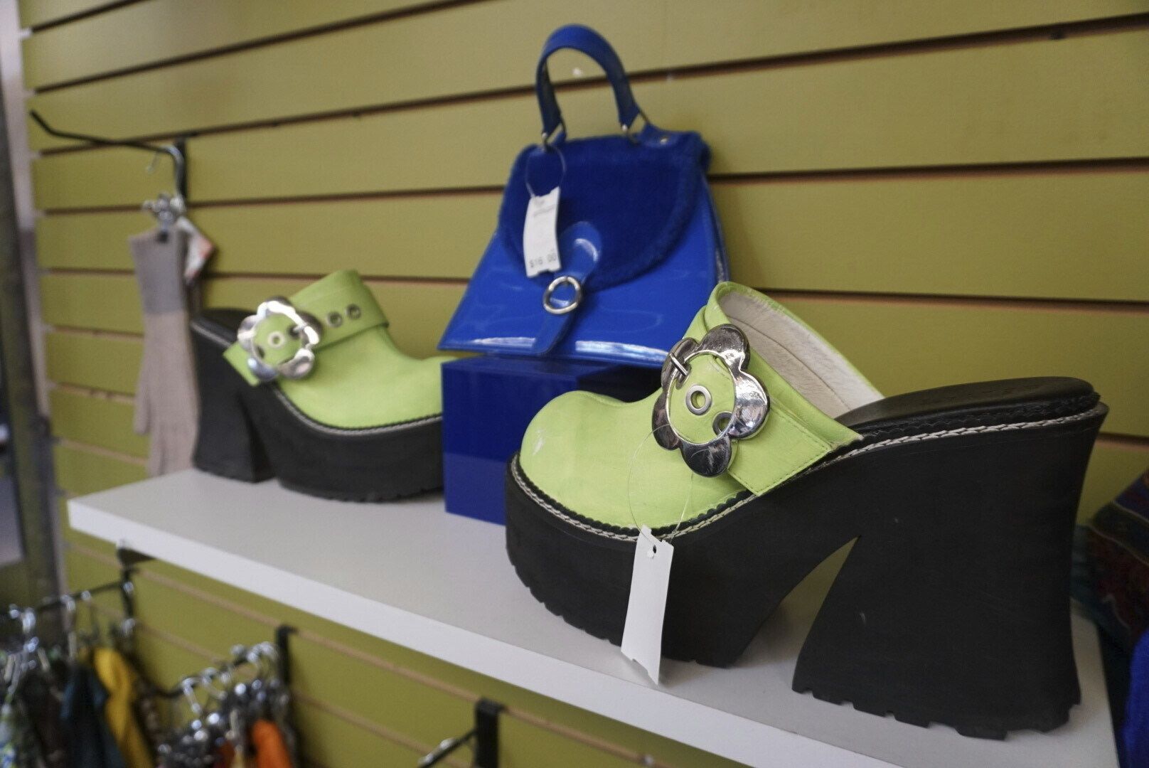 A pair of platform mule shoes and a bright blue bag are displayed at Apocalypse, a buy, sell and trade store in Boulder, Colo. on Saturday, July 12, 2025. (Nicky Andrews via AP)